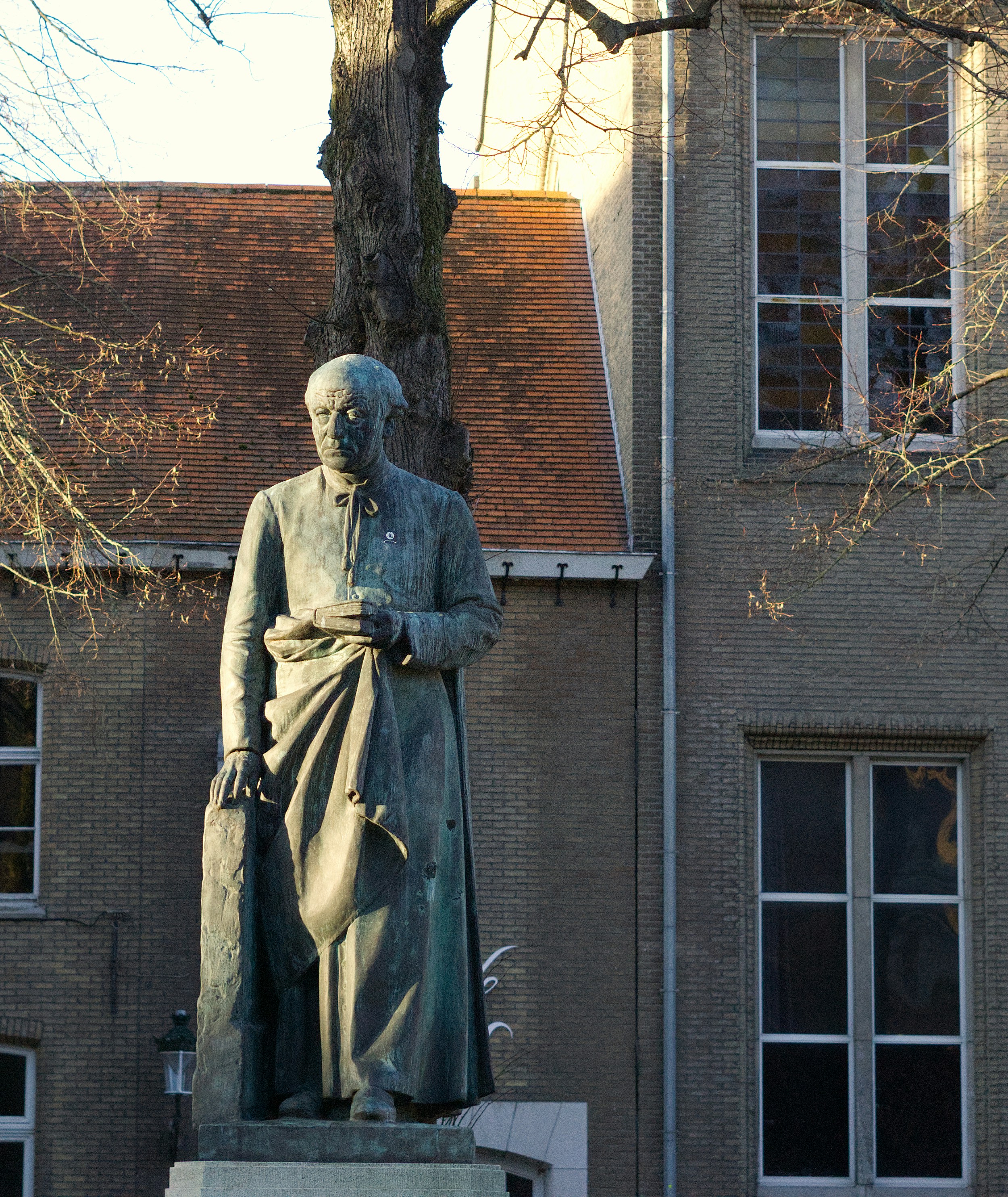 Bronze statue of a man in front of brick building.