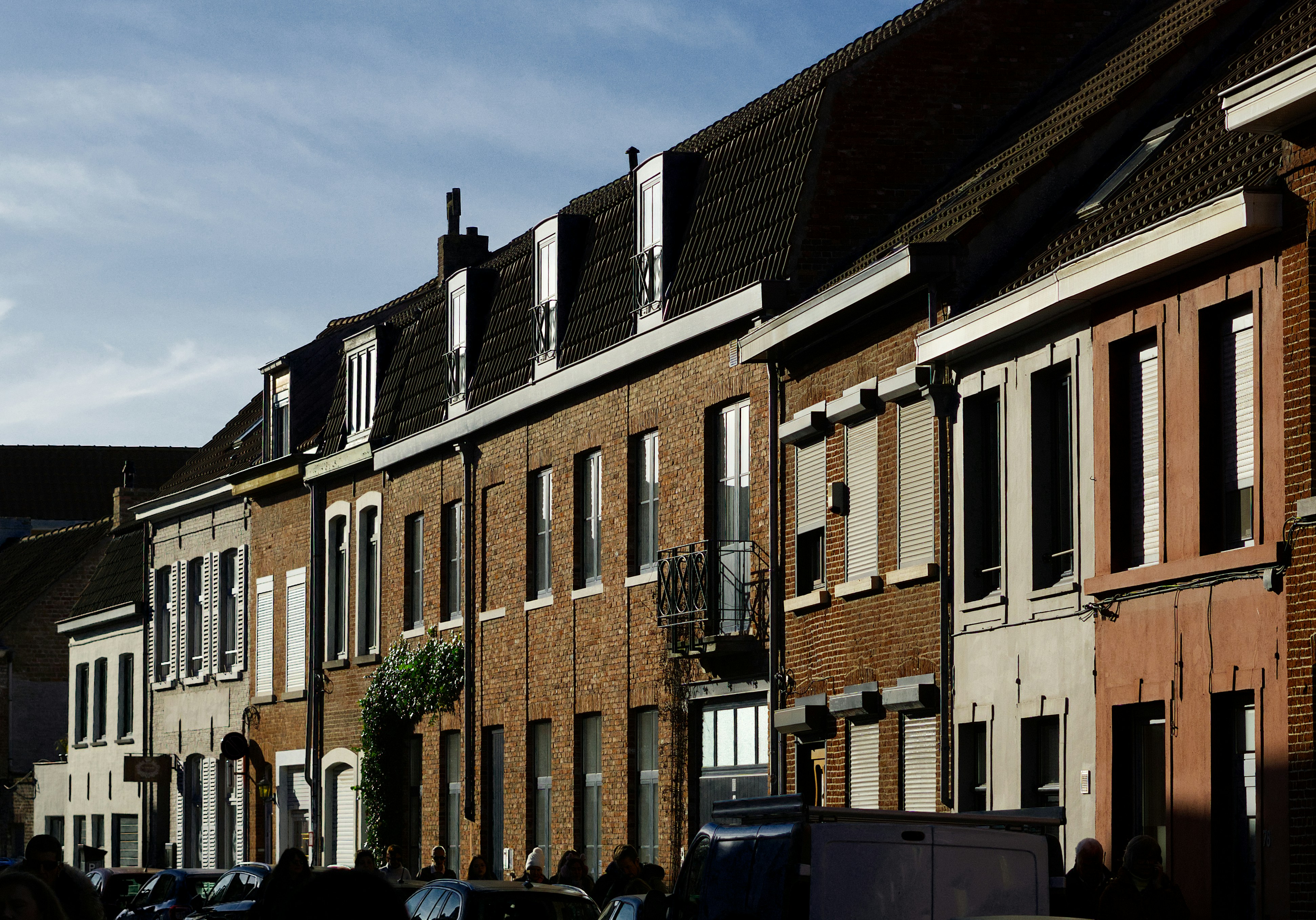 Row of brick houses with tall windows and tiled roofs.