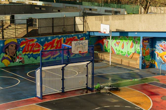 Graffiti-covered outdoor basketball court with a soccer goal.