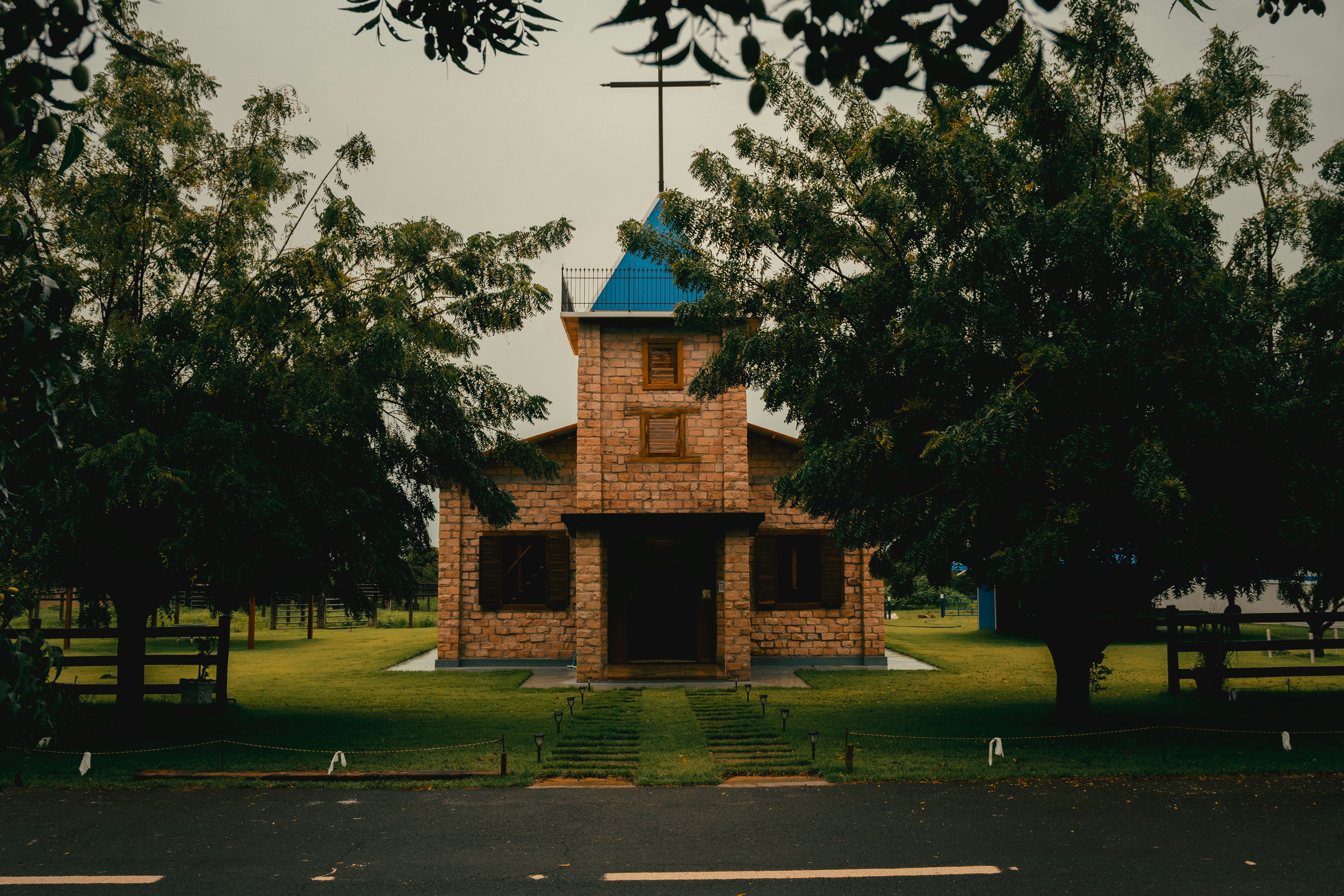 Small brick church with blue steeple and cross.