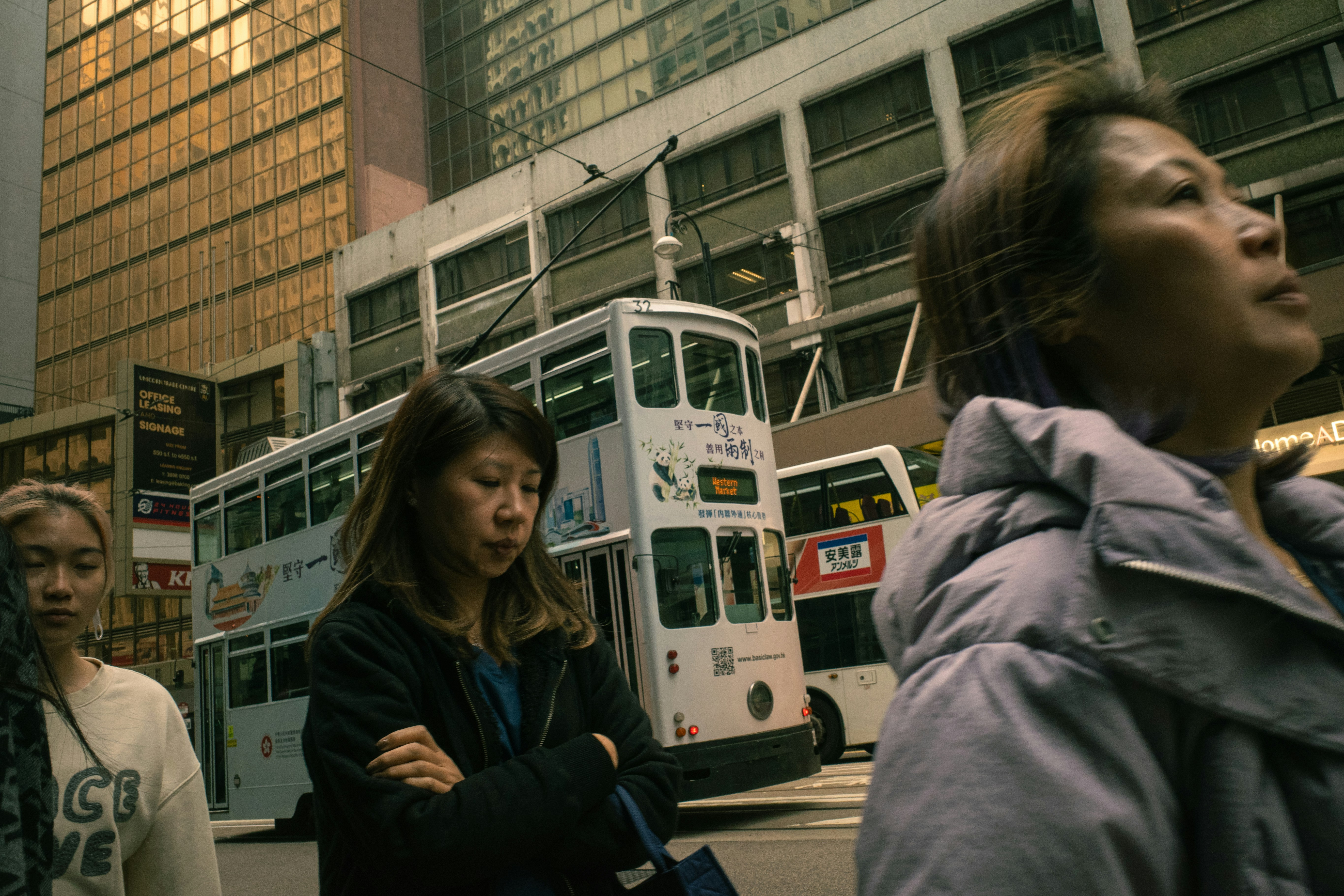 People walk past a tram in a city