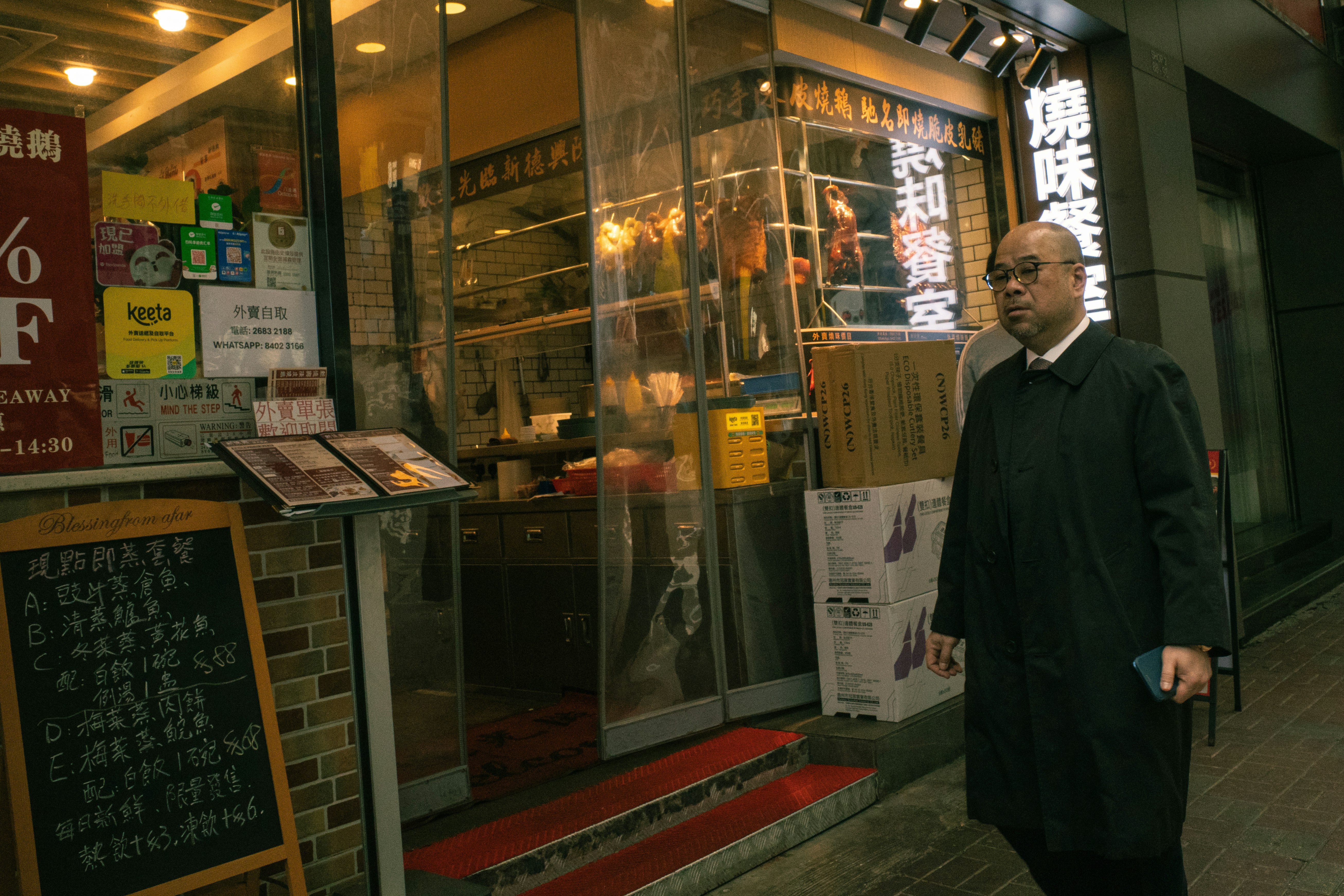 Man walks past a restaurant at night.