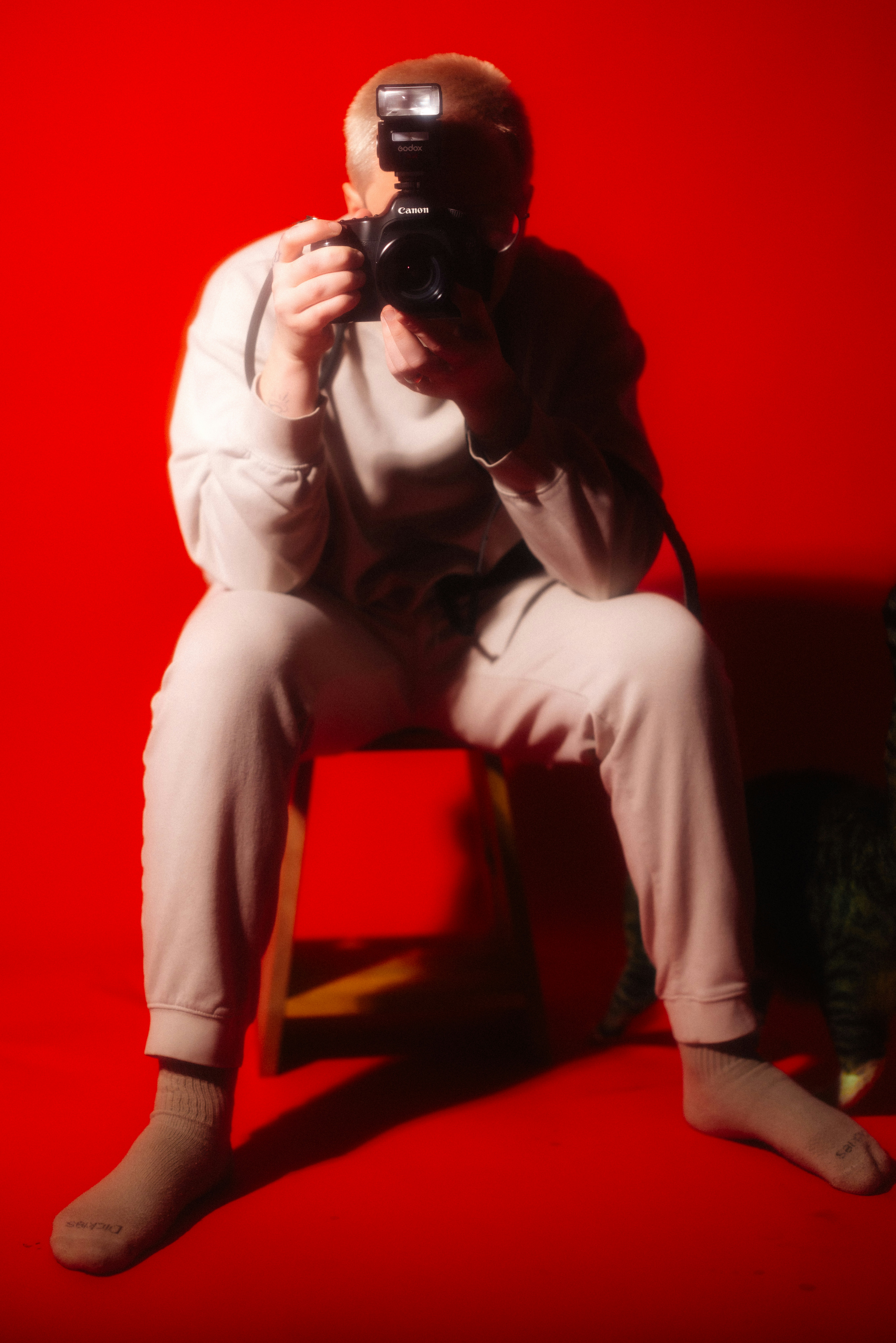 Person with camera takes a photo against red background.