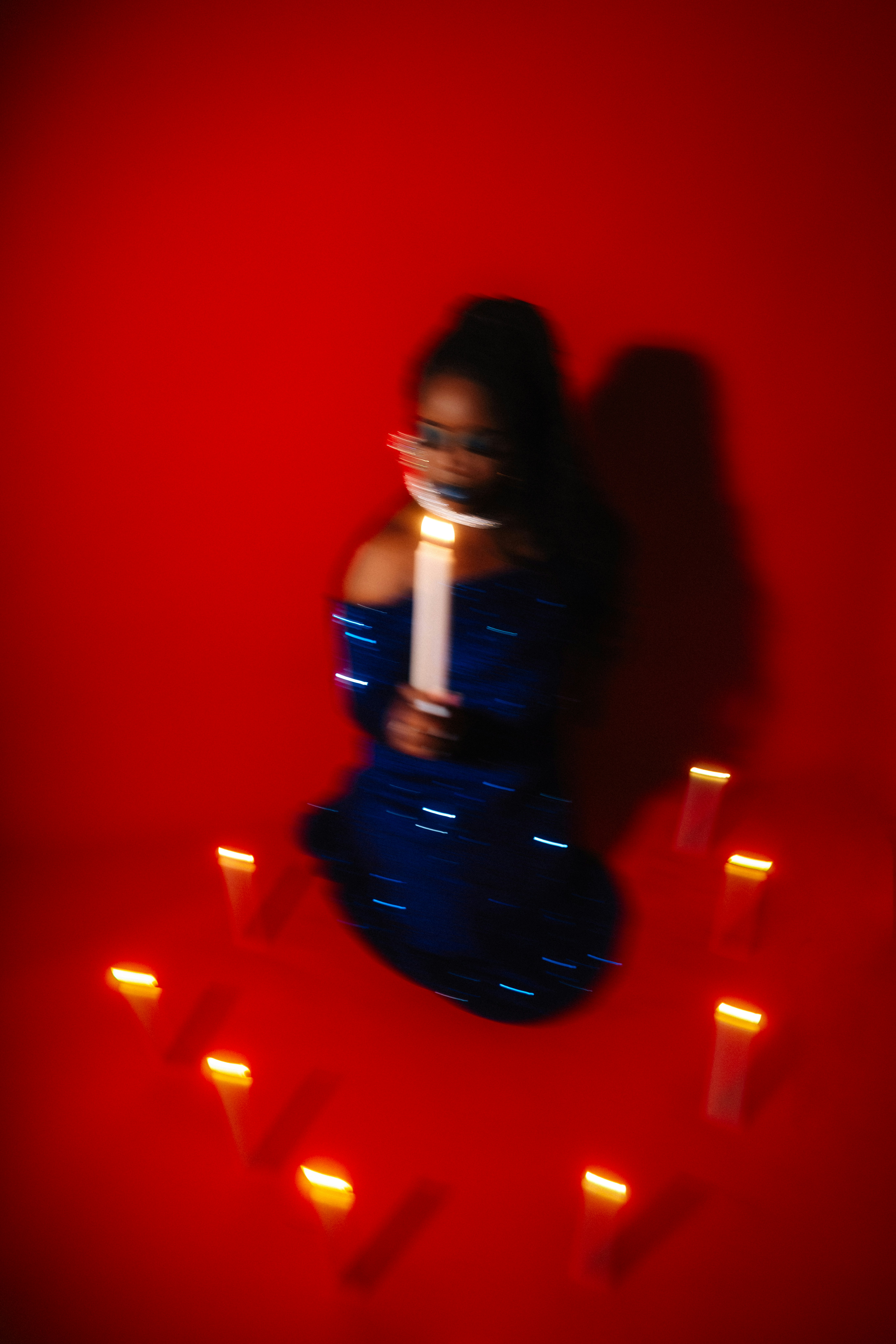 Woman in blue dress holding candle with candles around her