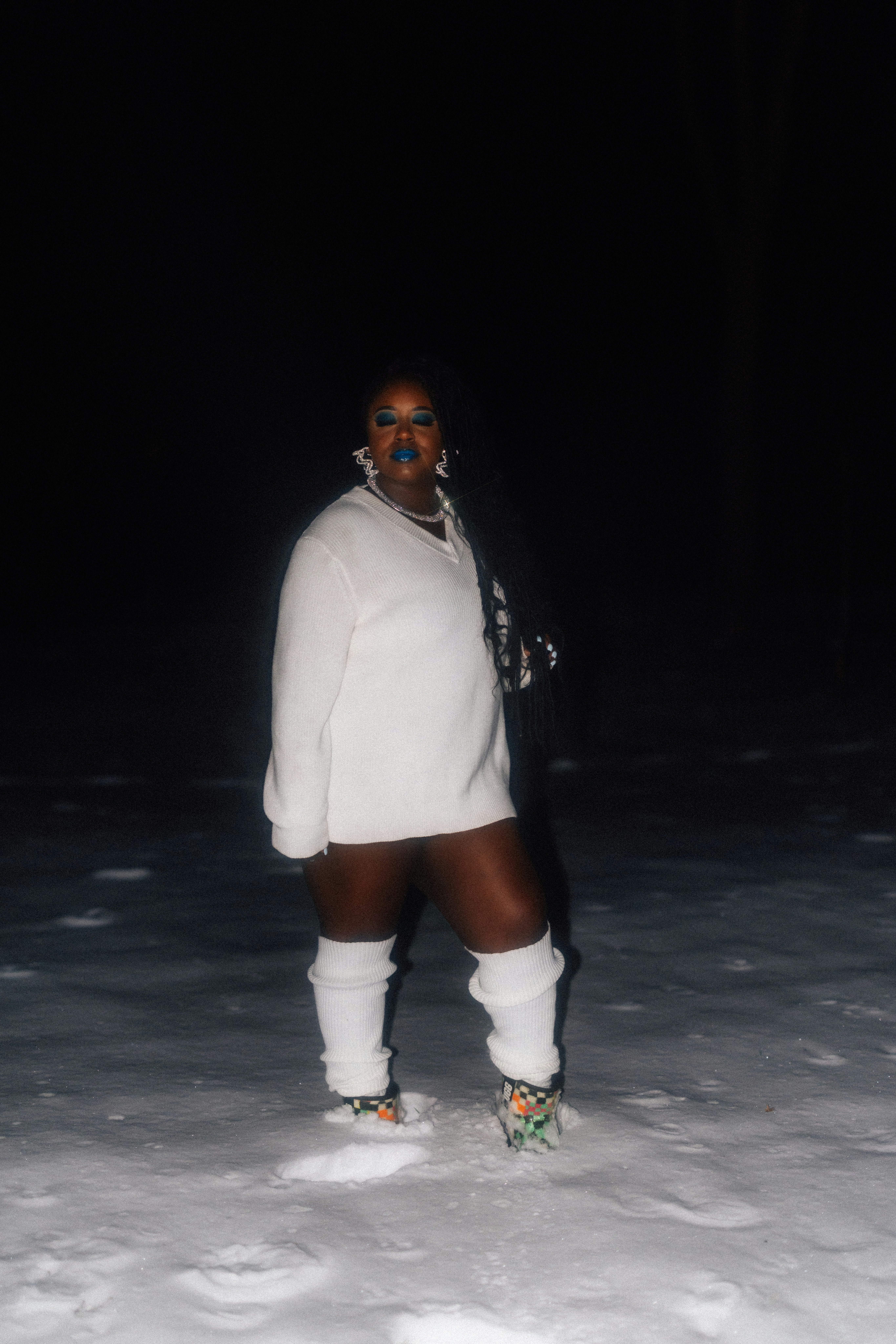 A person stands in the snow at night.