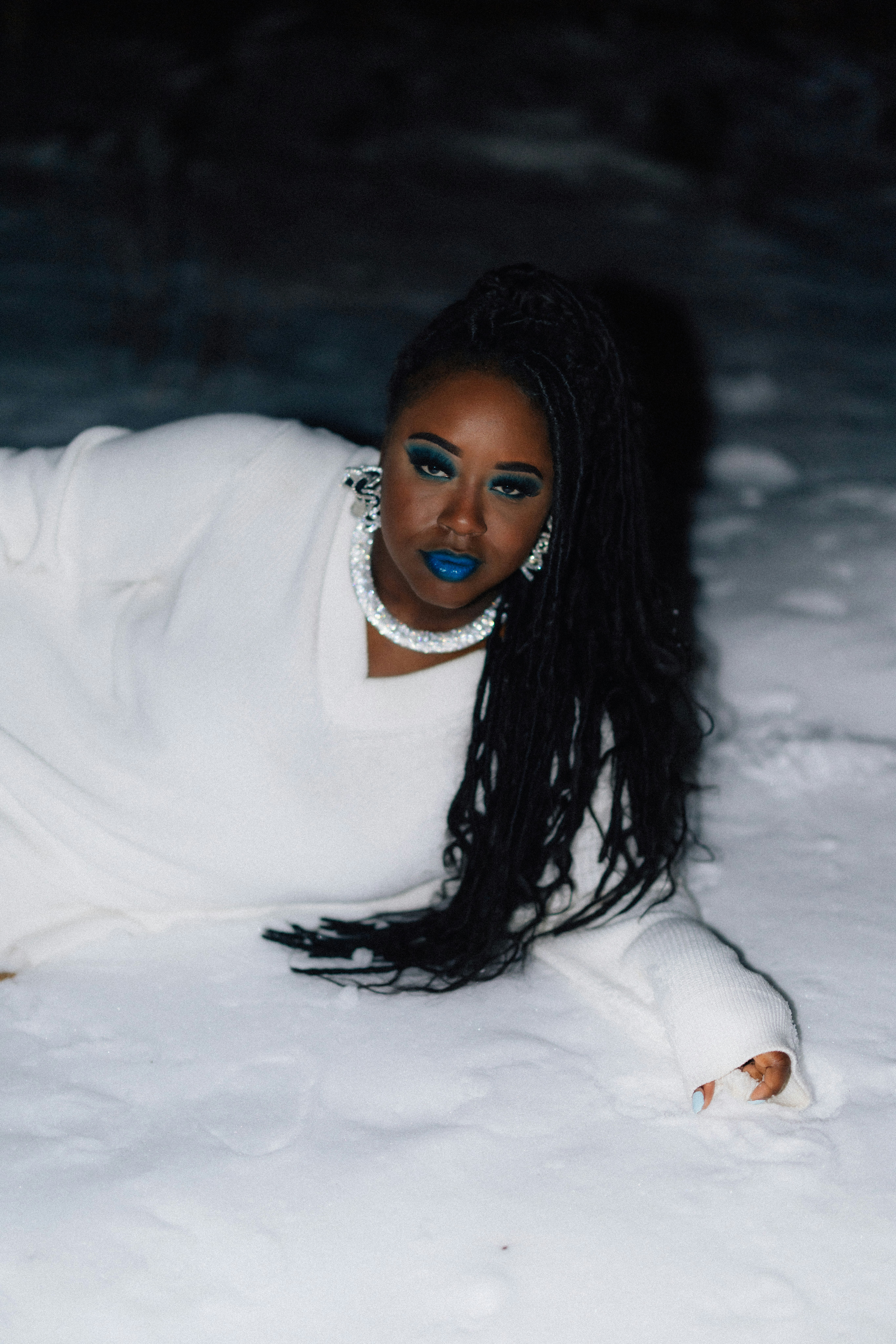 Woman in white sweater lying in snow