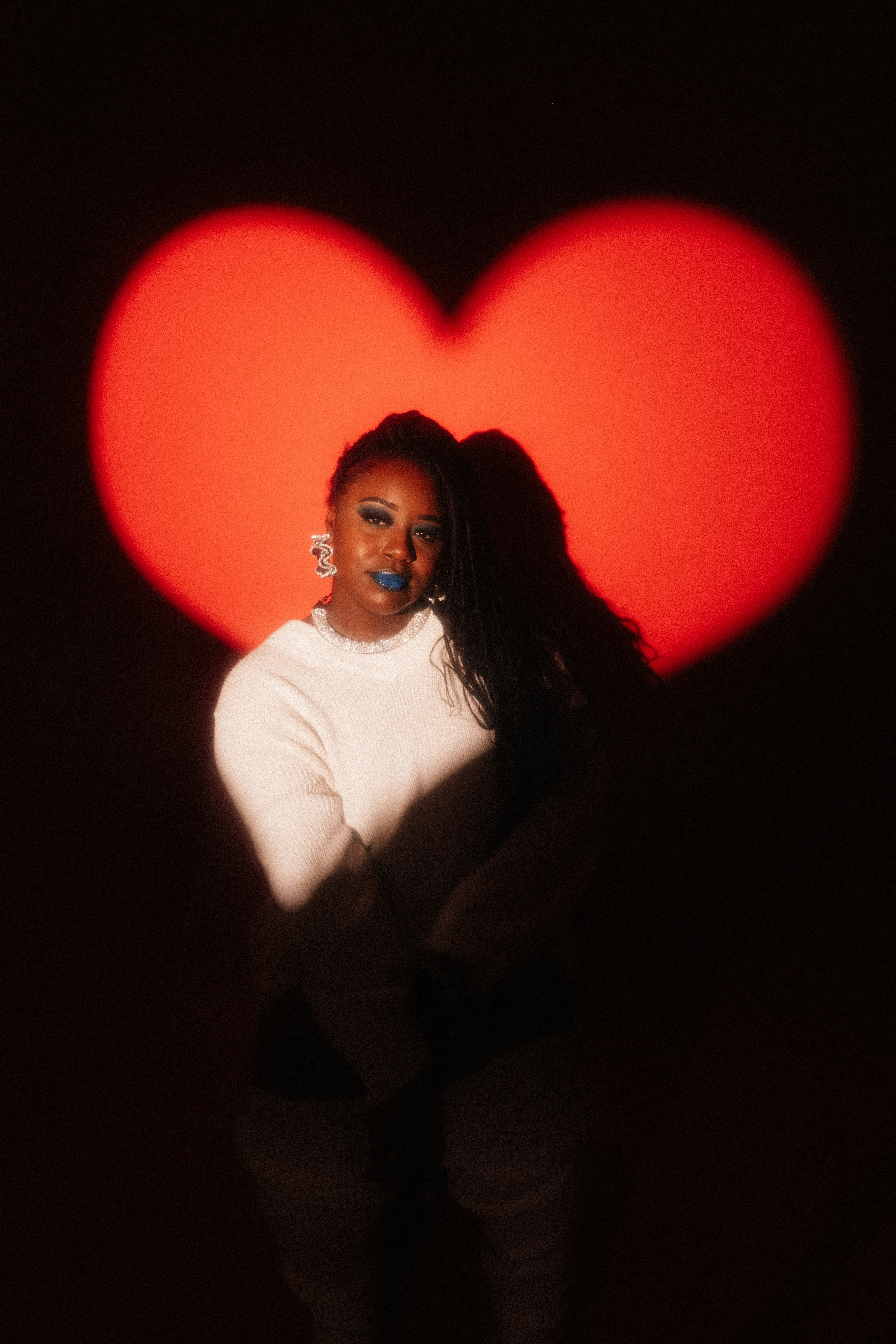 Woman with blue lipstick in front of red heart light