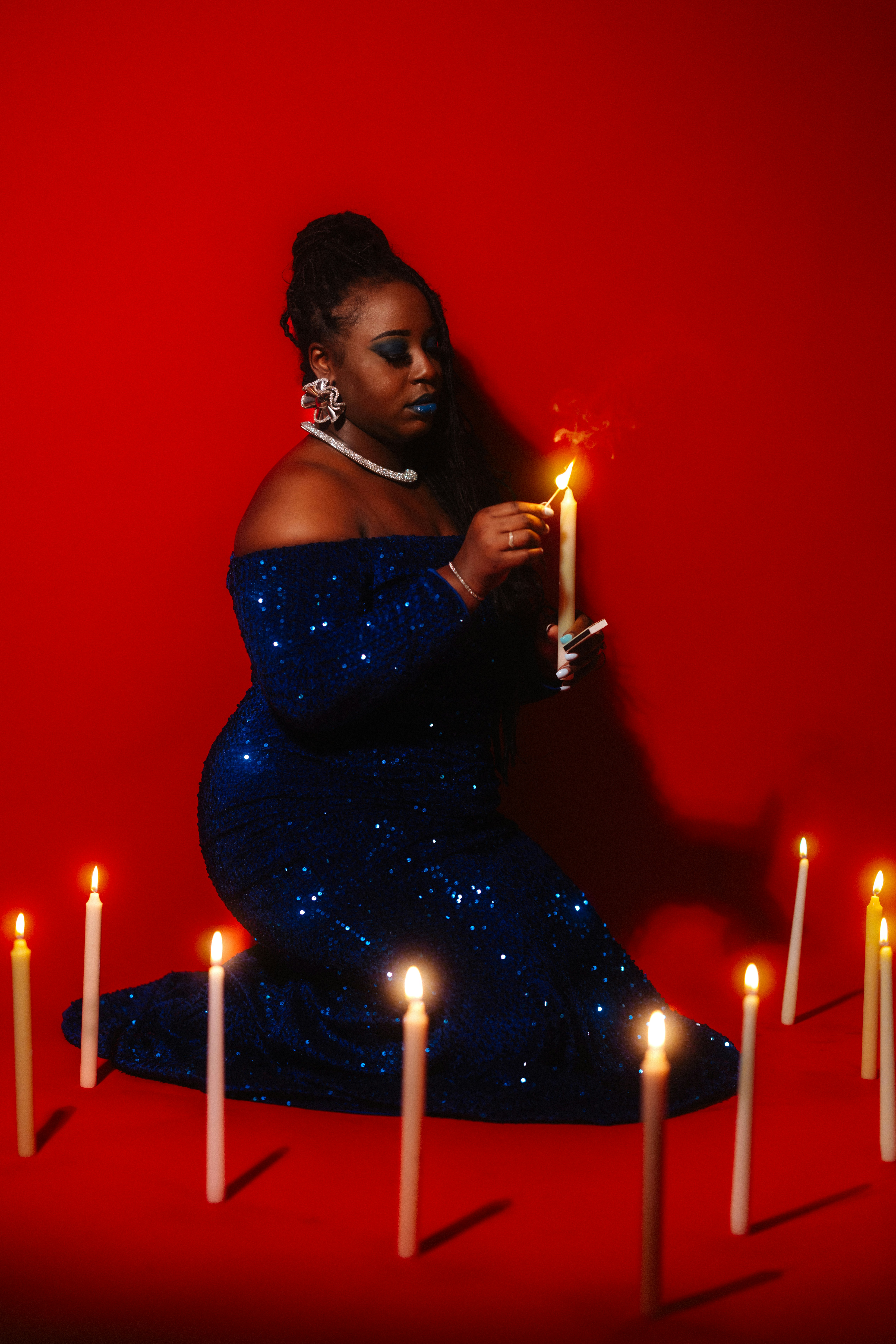 Woman in blue dress lights candle surrounded by lit candles