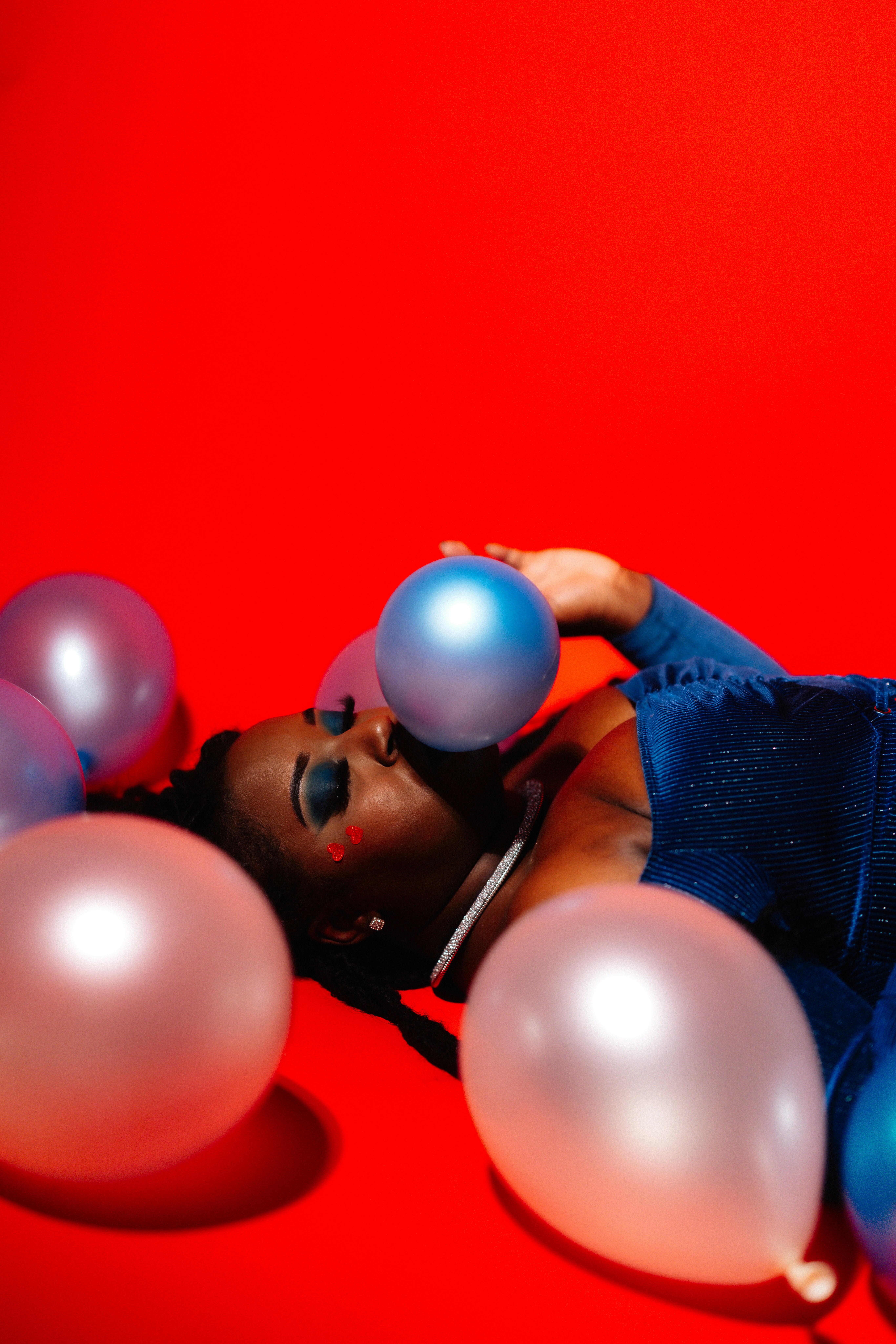 Woman in blue dress with balloons on red background