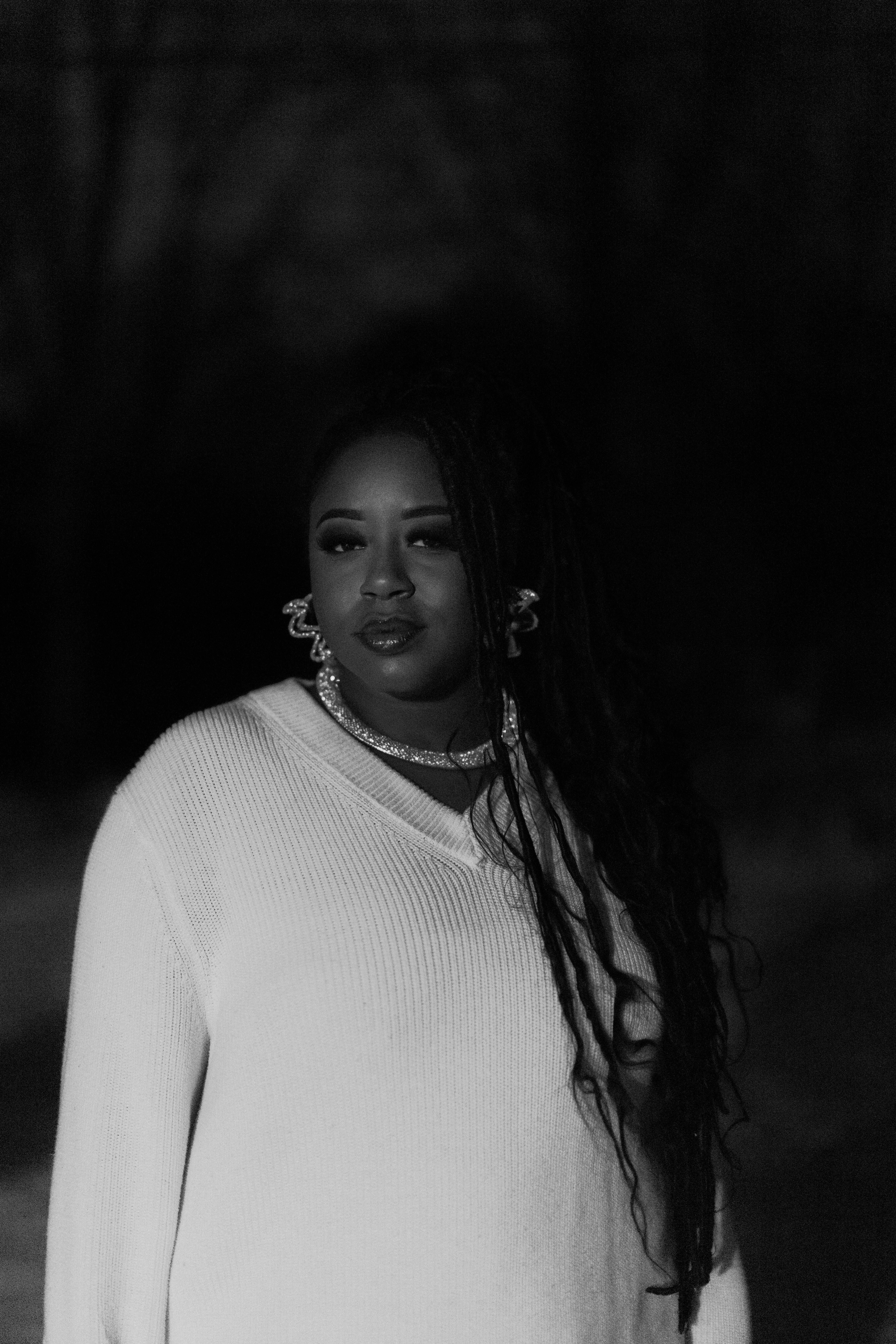 A woman with long braids wearing a white sweater.