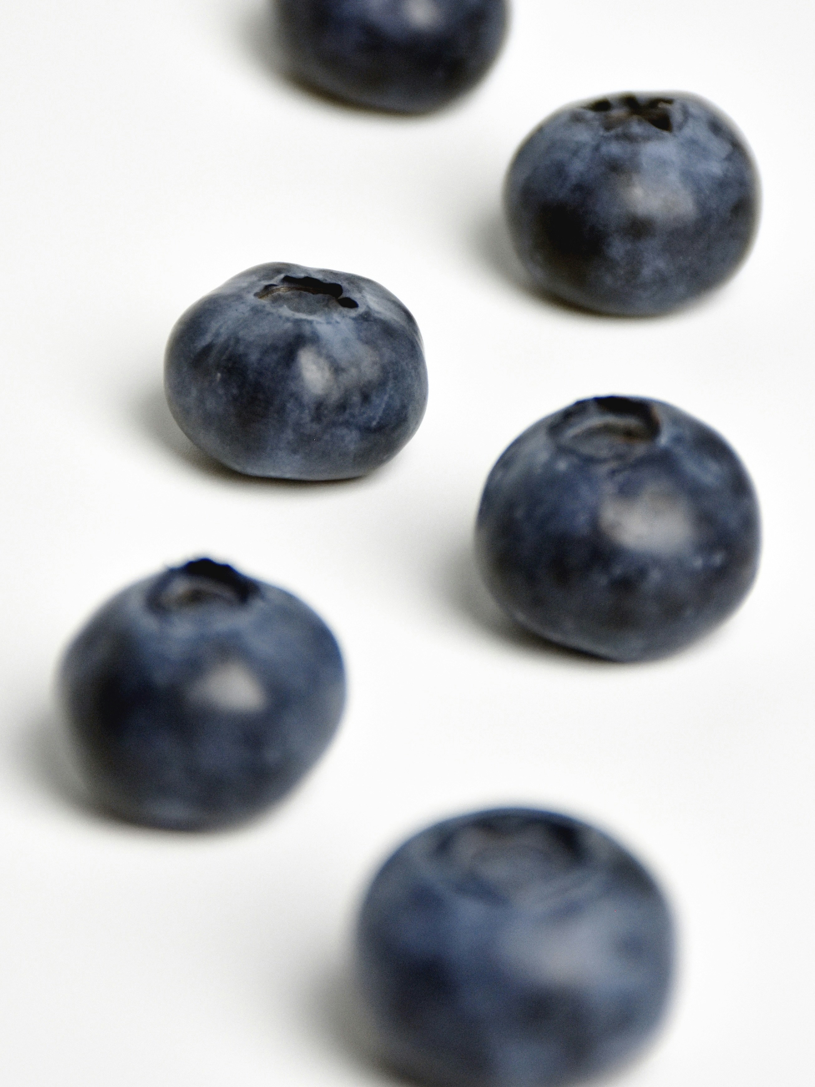 Several blueberries scattered on a white surface