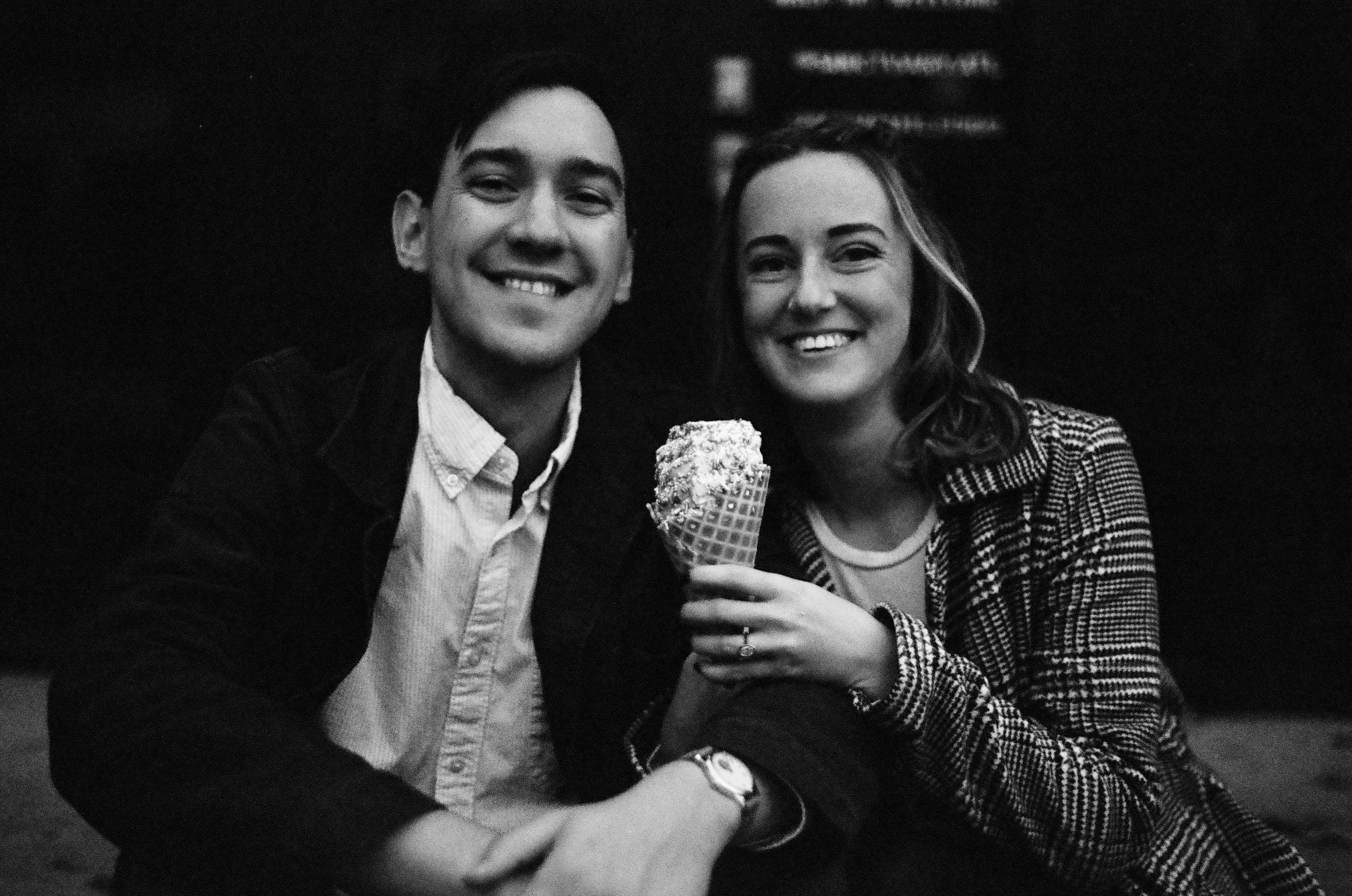 A smiling couple shares an ice cream cone