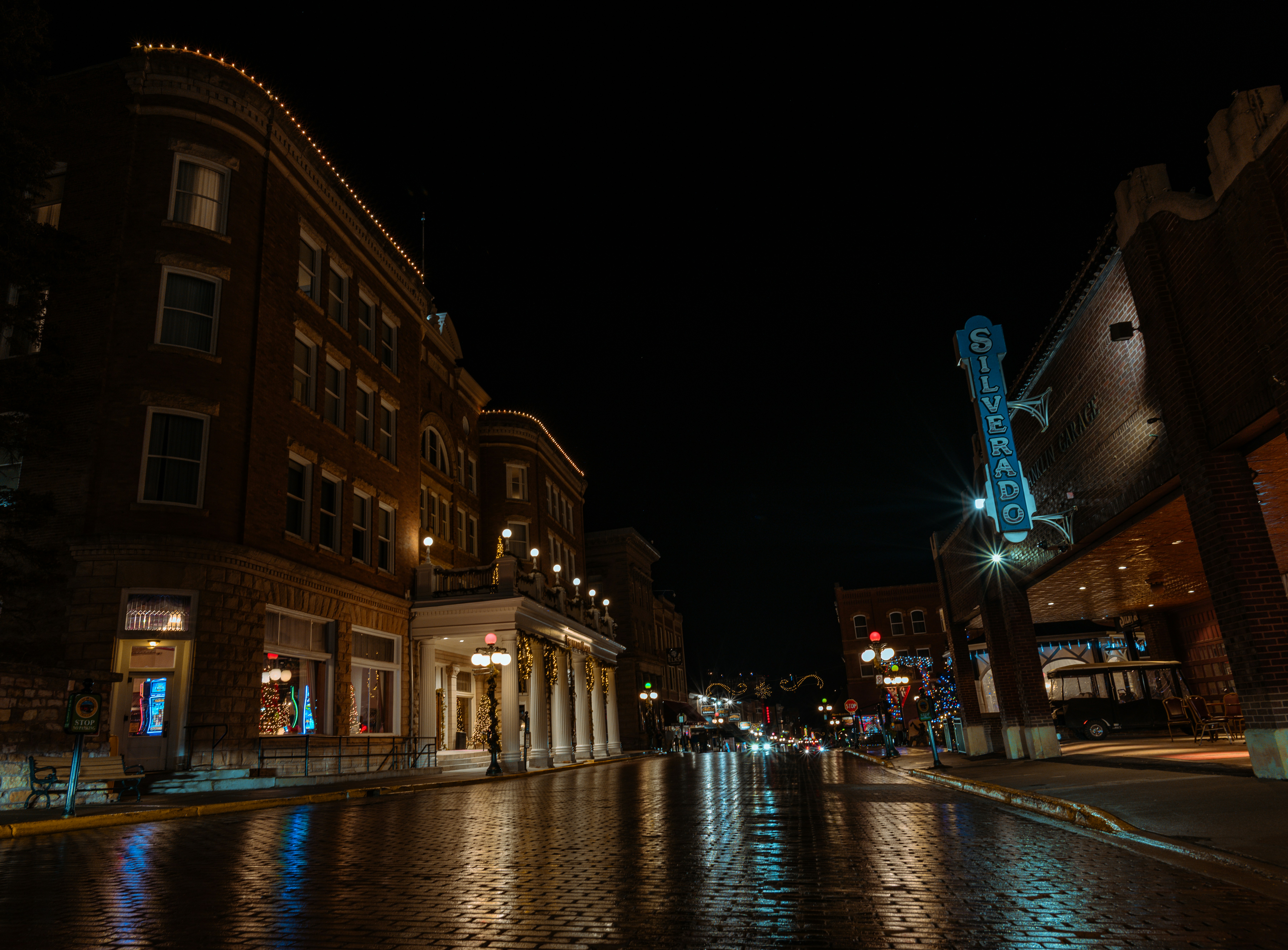 La calle mojada refleja las luces de los edificios por la noche
