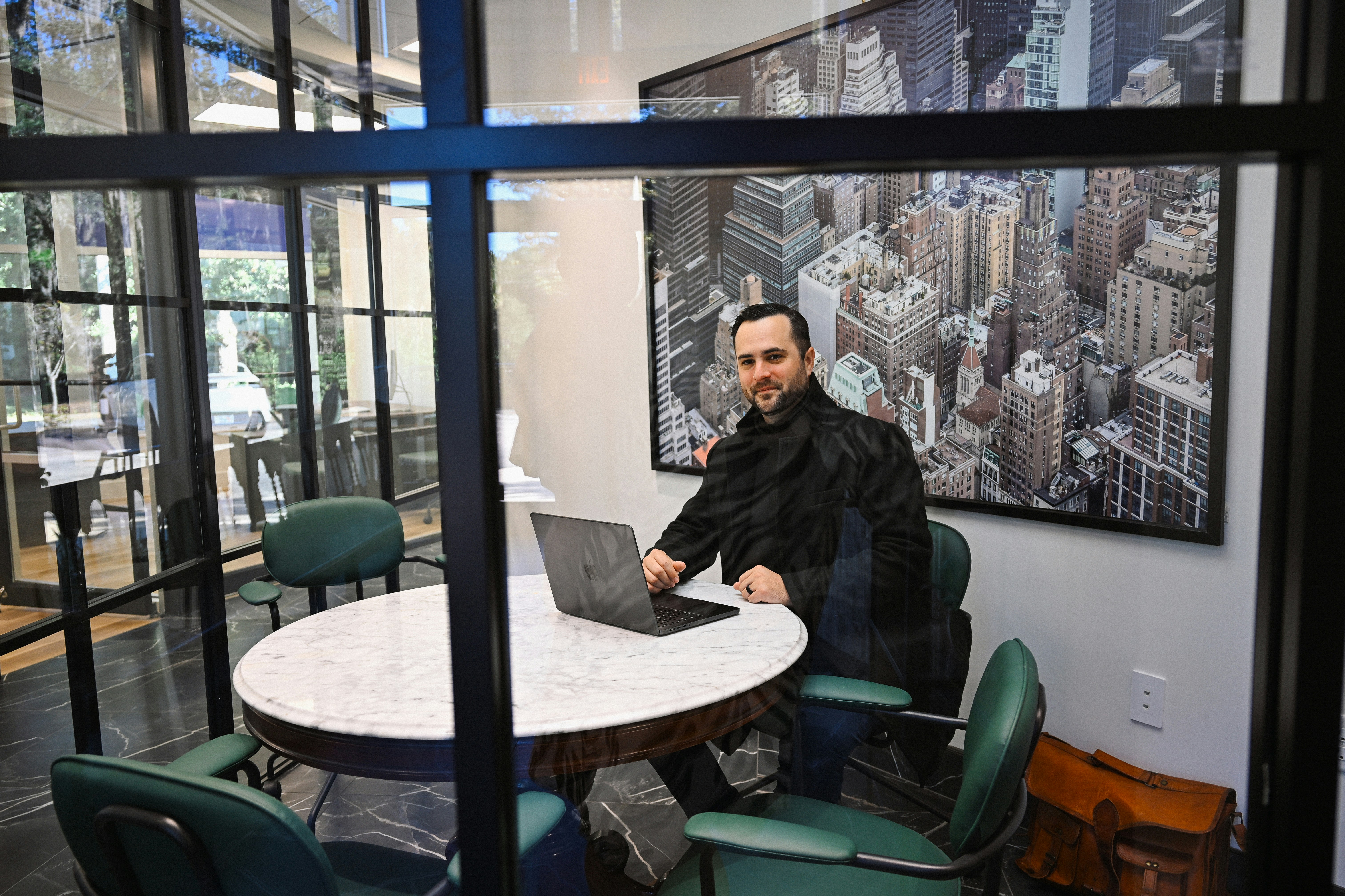 executive typing on slim laptop in glass conference room