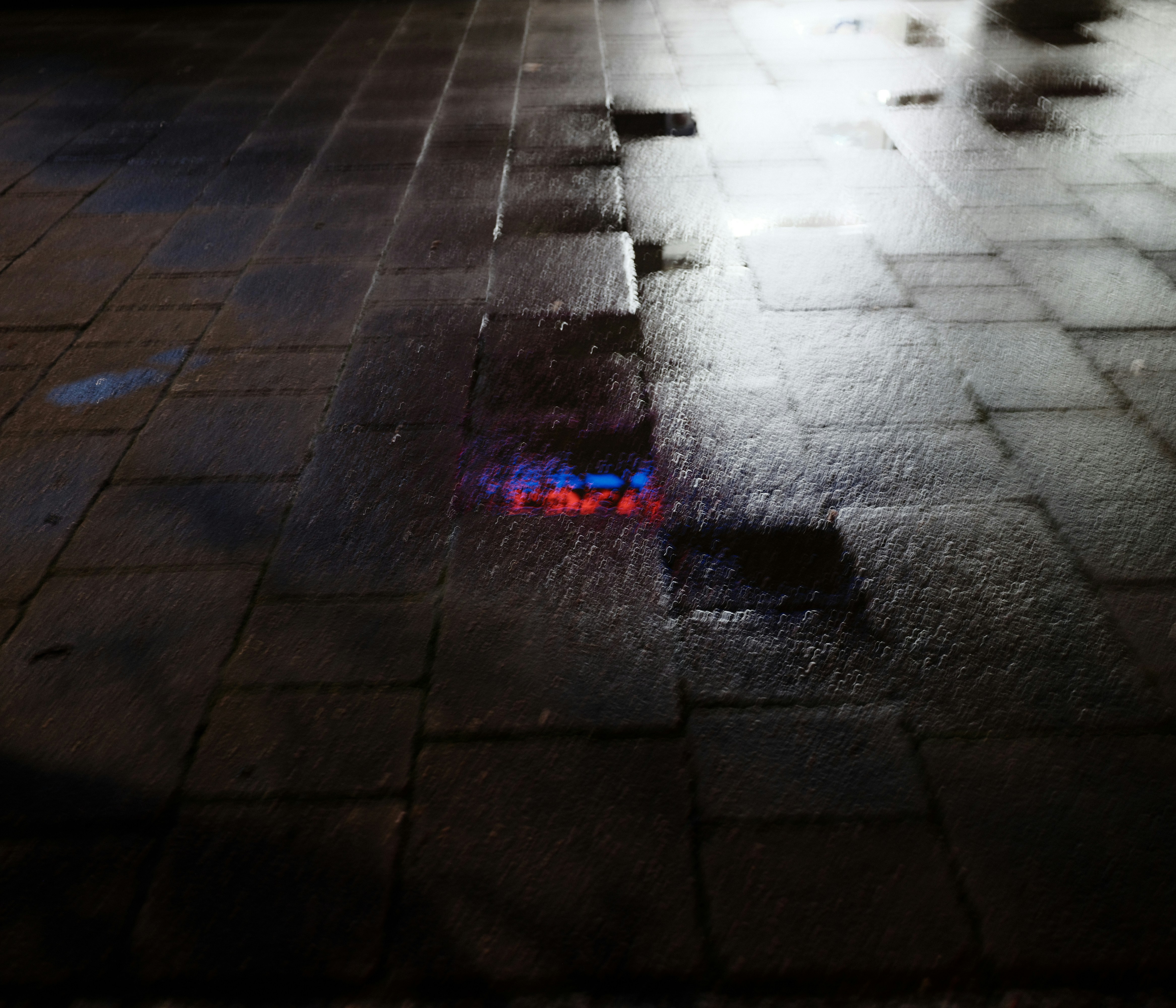 Wet pavement reflecting colorful lights at night