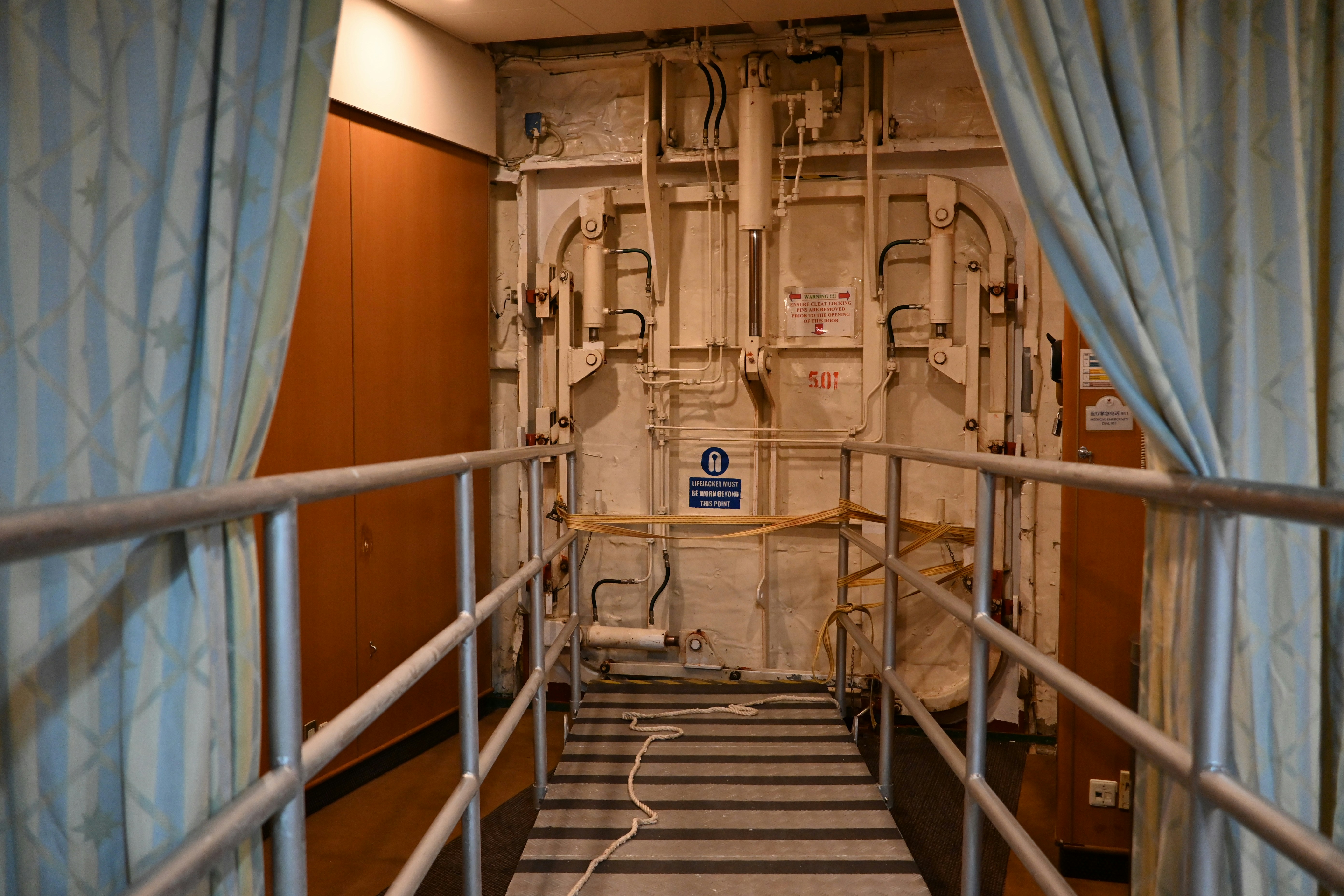 Un passaggio metallico conduce a una grande porta industriale.