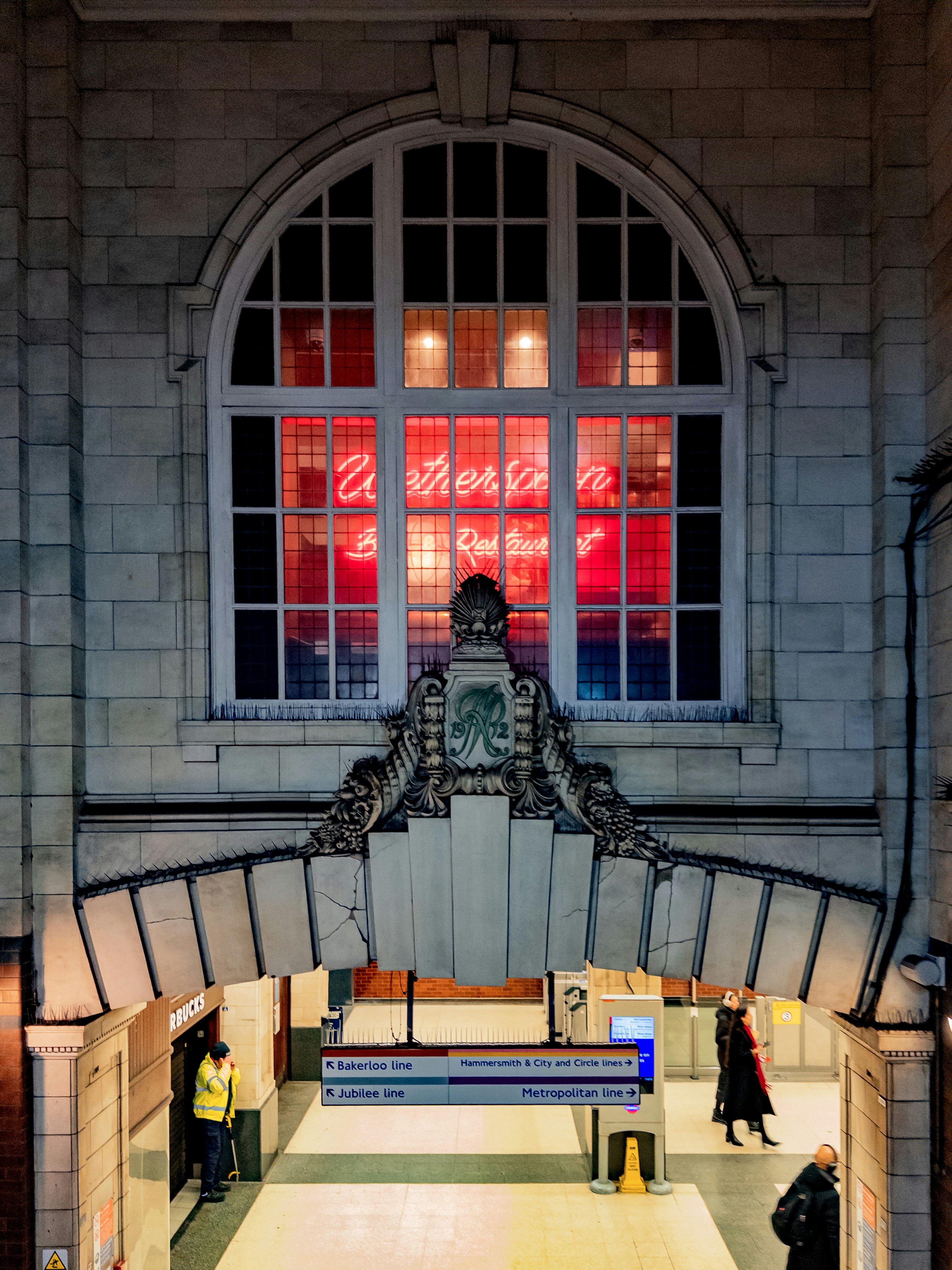 Grand arched window with red neon sign at night.