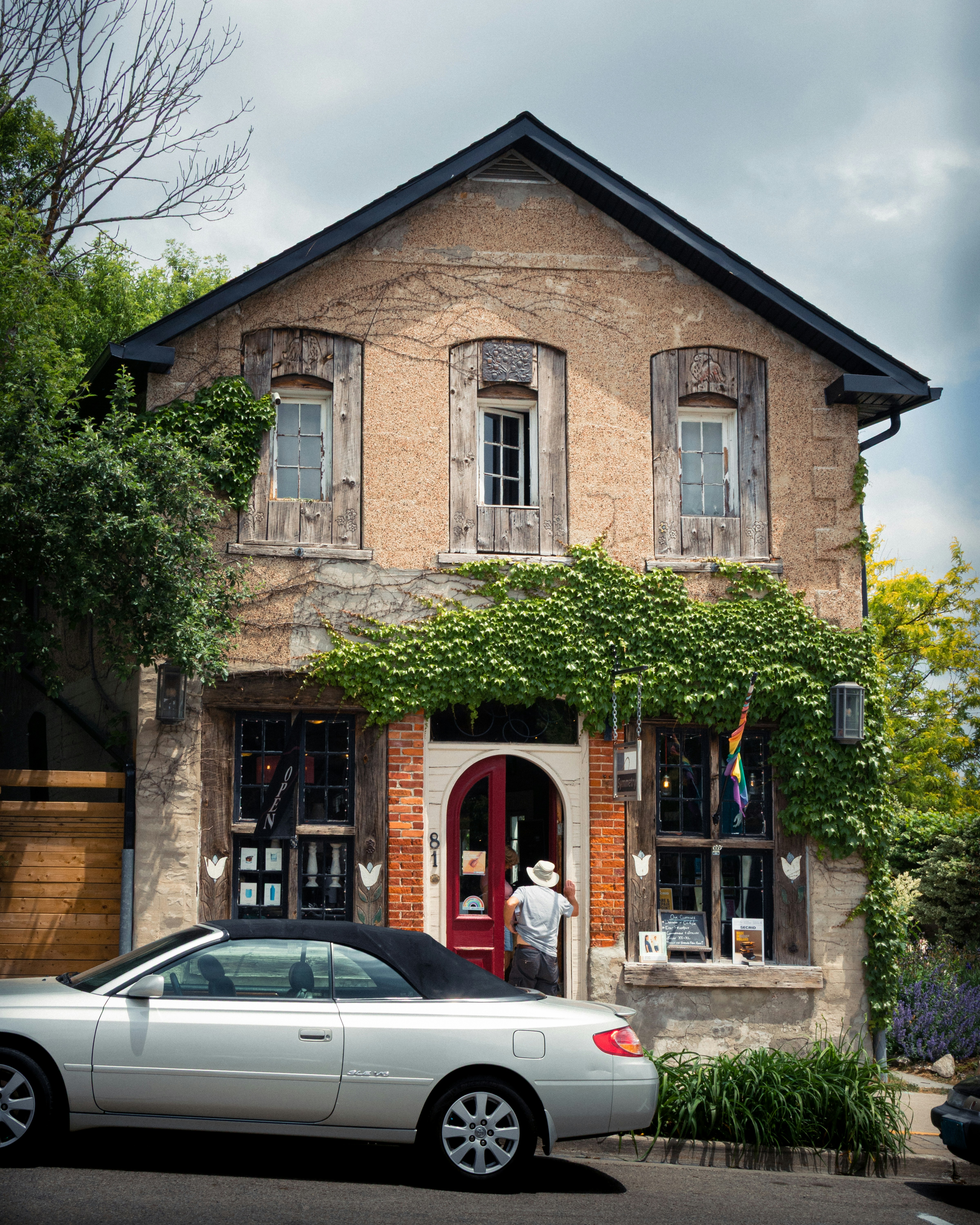 A person enters a charming store with a white convertible.