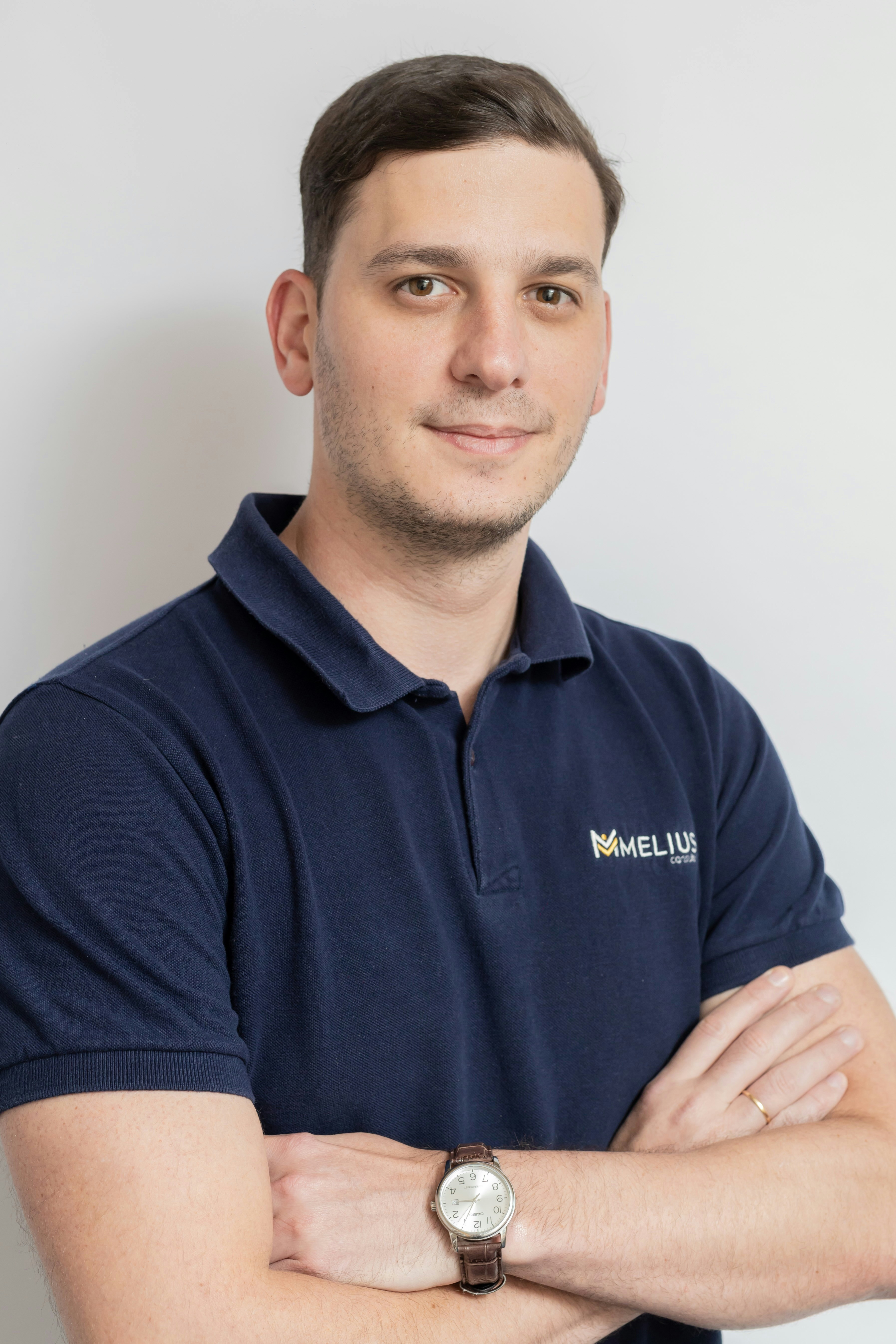 A man in a navy polo shirt with arms crossed.