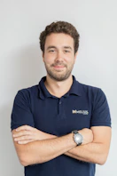 Man wearing a dark blue polo shirt with arms crossed