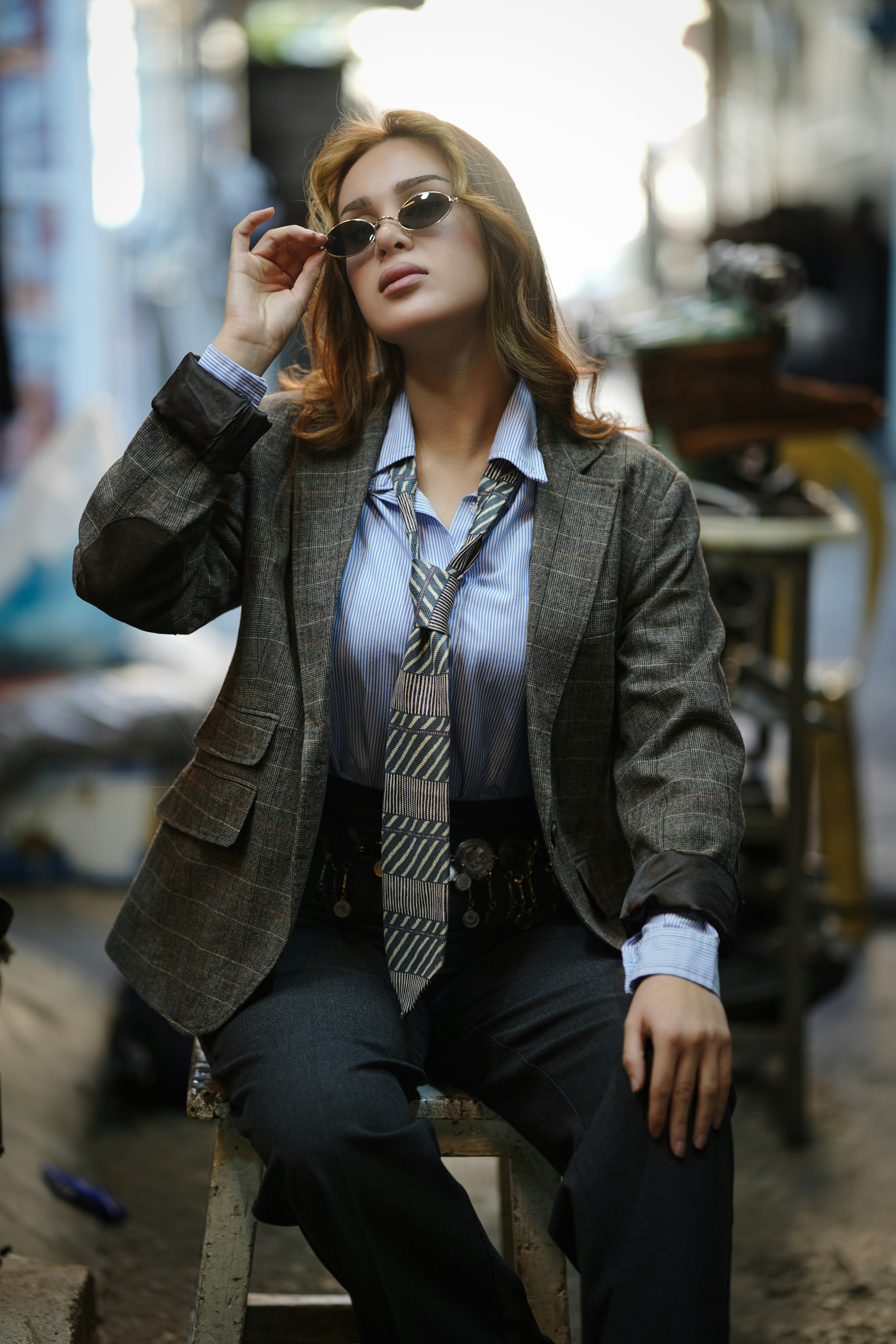 Woman in a suit adjusts her sunglasses outdoors