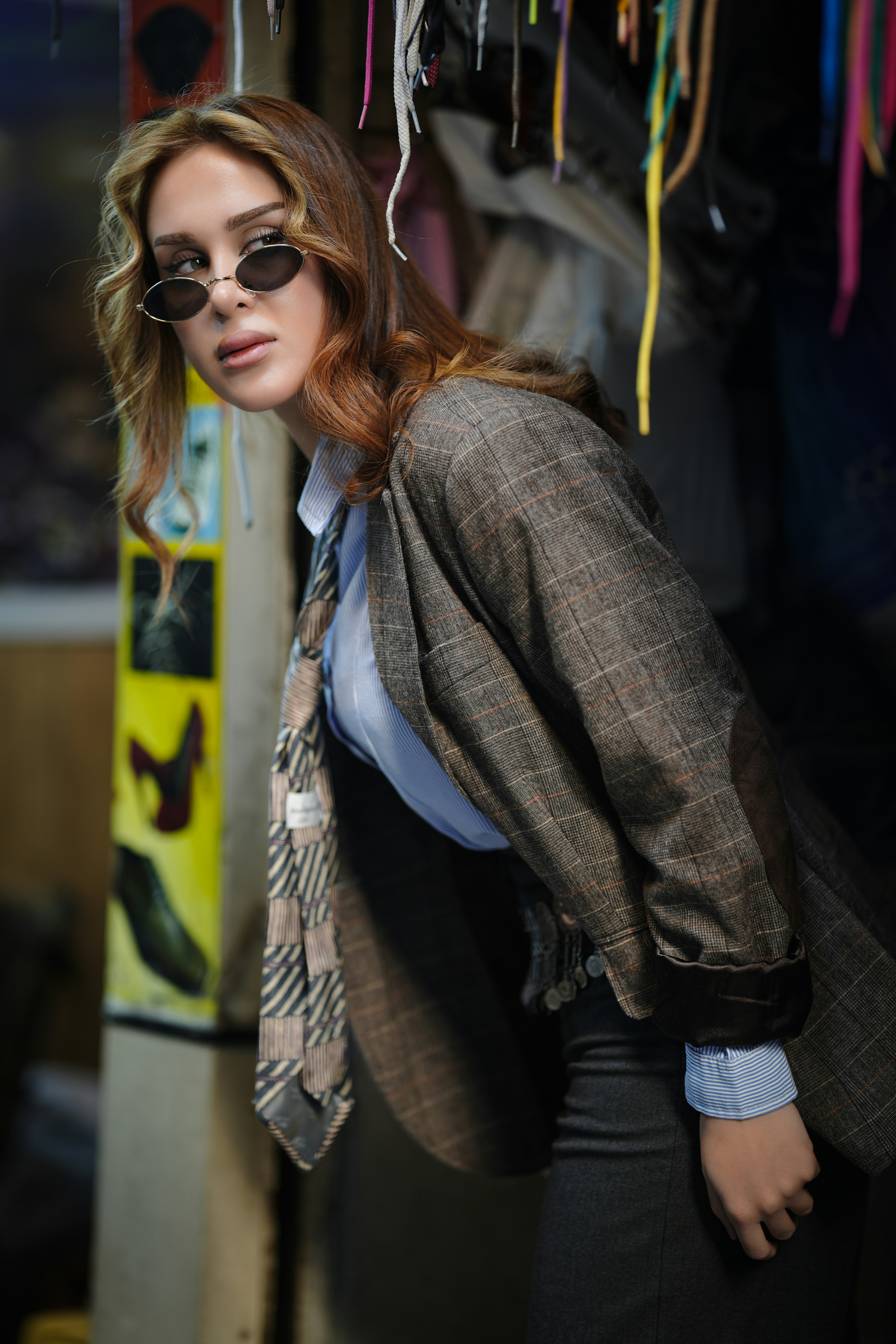 Woman in blazer and sunglasses looking over shoulder.