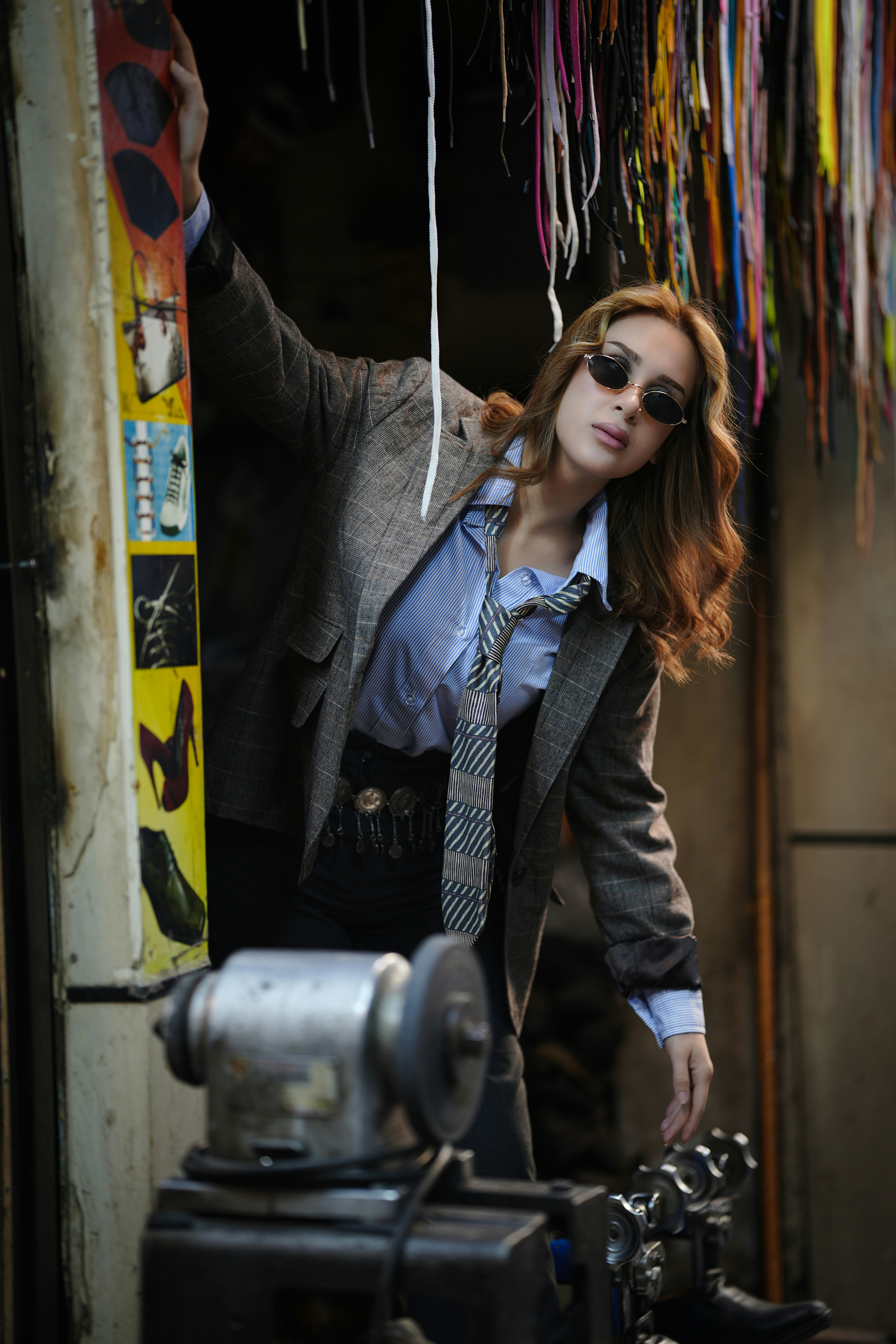 Woman in blazer and tie stands by colorful threads