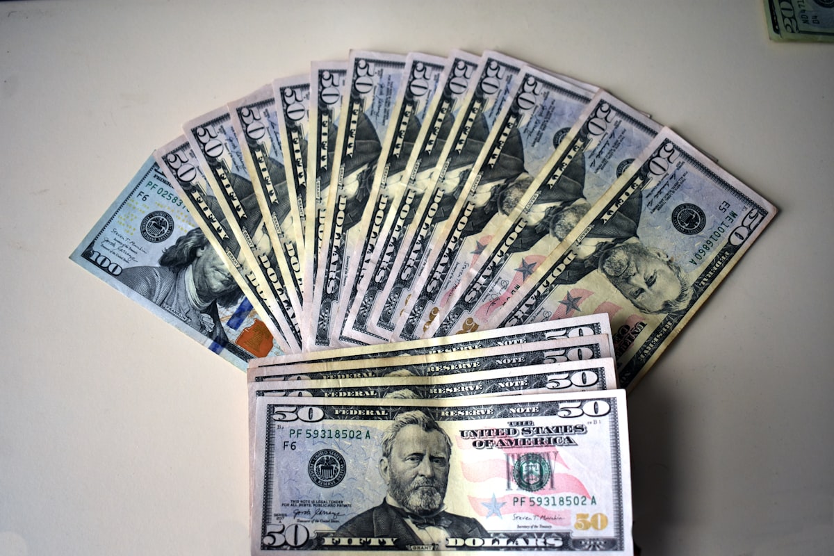 Fan of fifty dollar bills spread on a white surface