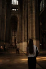 Woman walking through a grand cathedral interior.