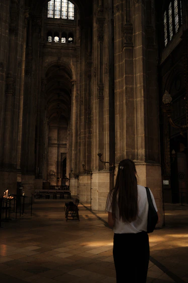 Woman walking through a grand cathedral interior.
