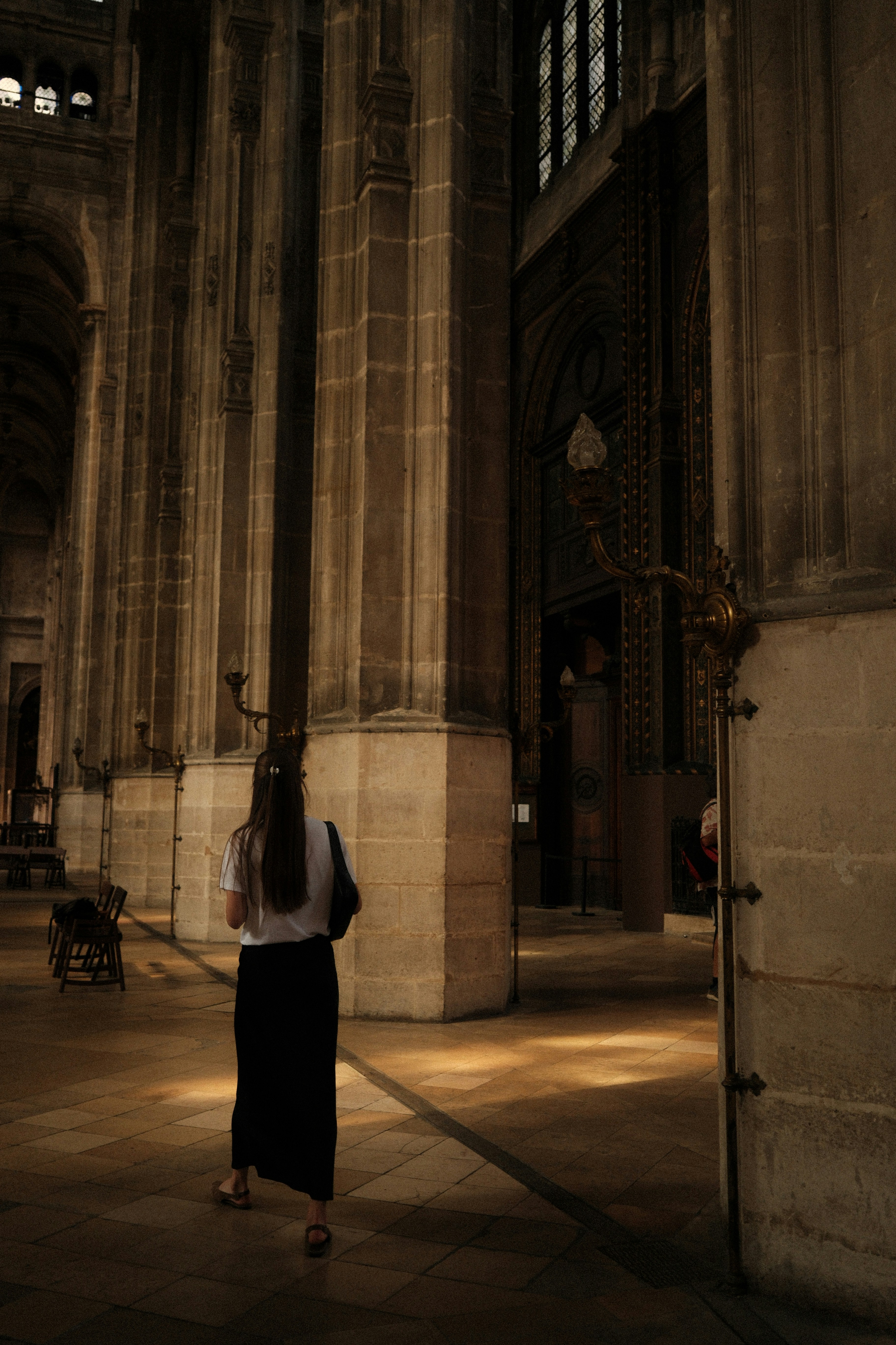Une femme descend une grande salle de cathédrale.
