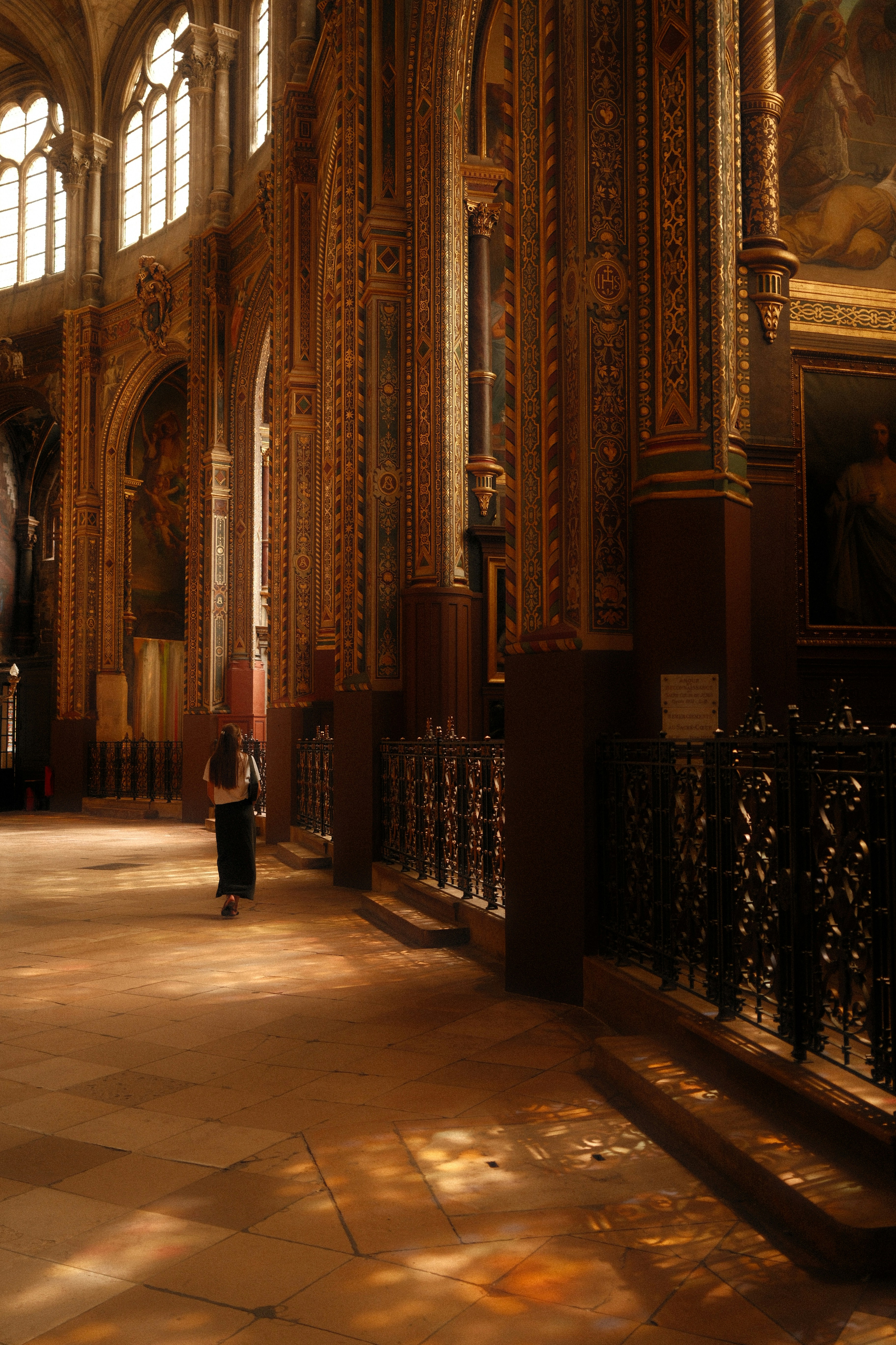 Une personne traverse l’intérieur d’une cathédrale baignée de soleil.