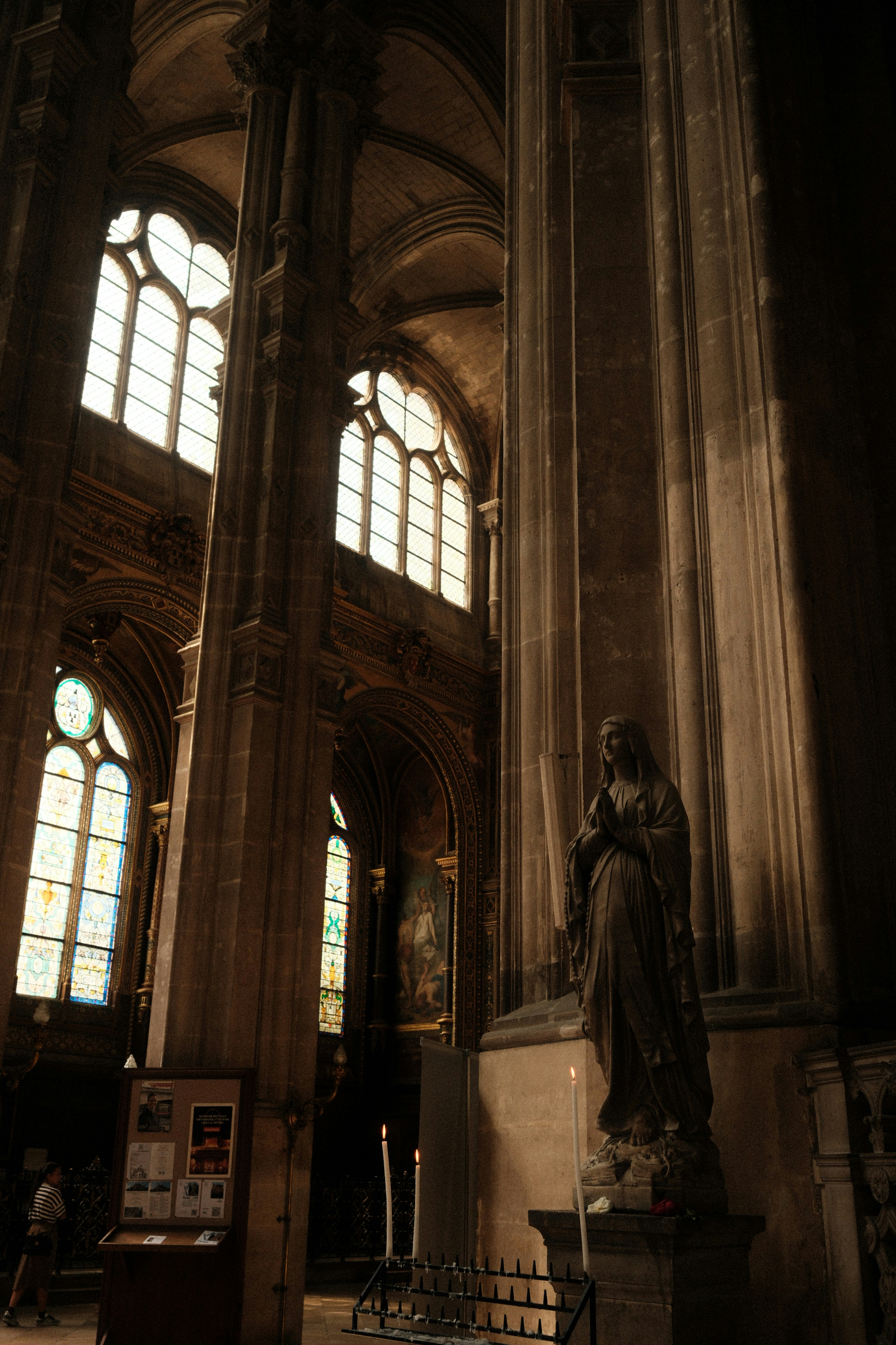 Statue d’une femme priant à l’intérieur d’une grande cathédrale.