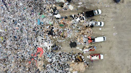 Aerial view of a landfill with scattered trash and vehicles.