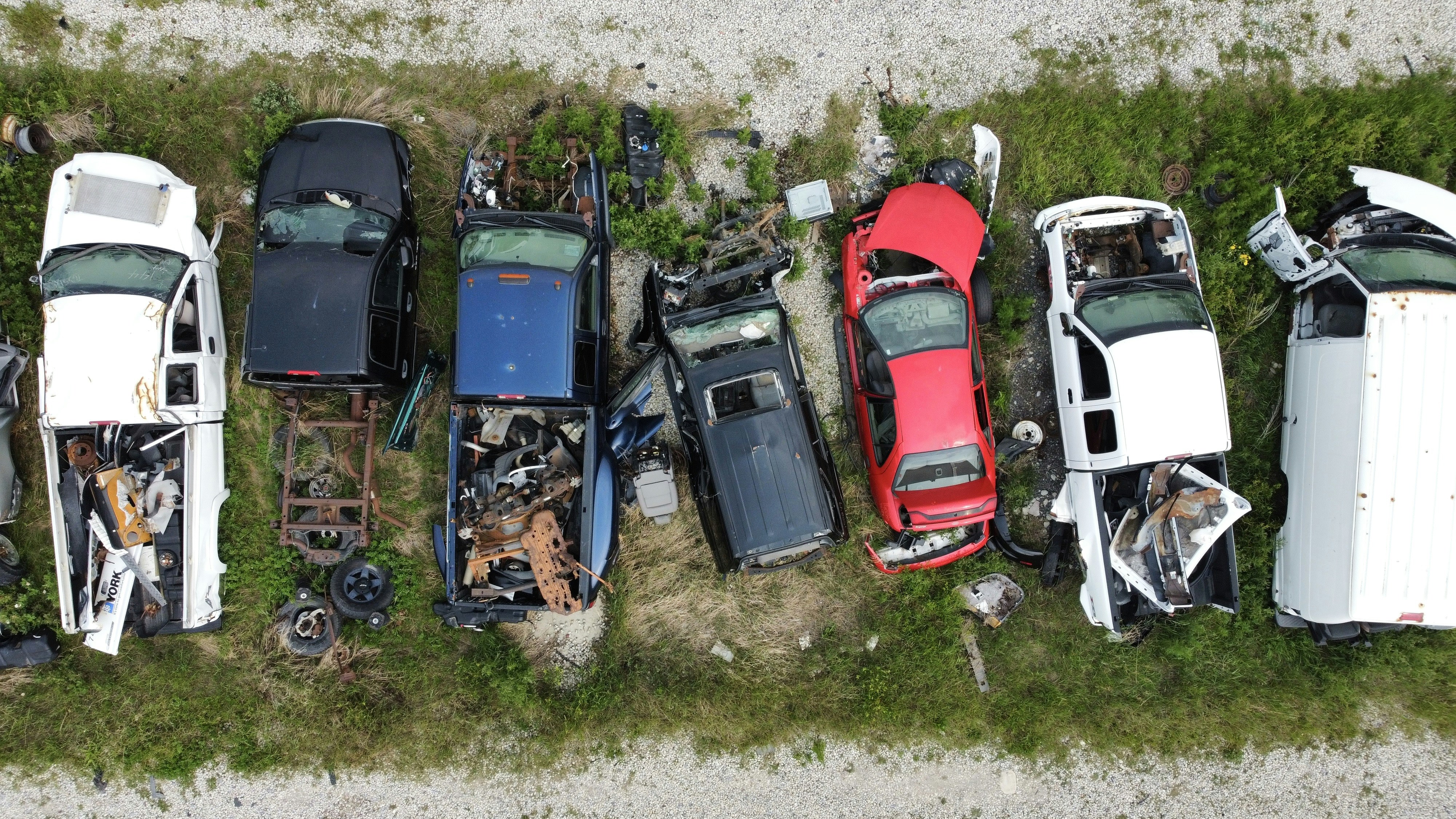Row of abandoned cars in a grassy field