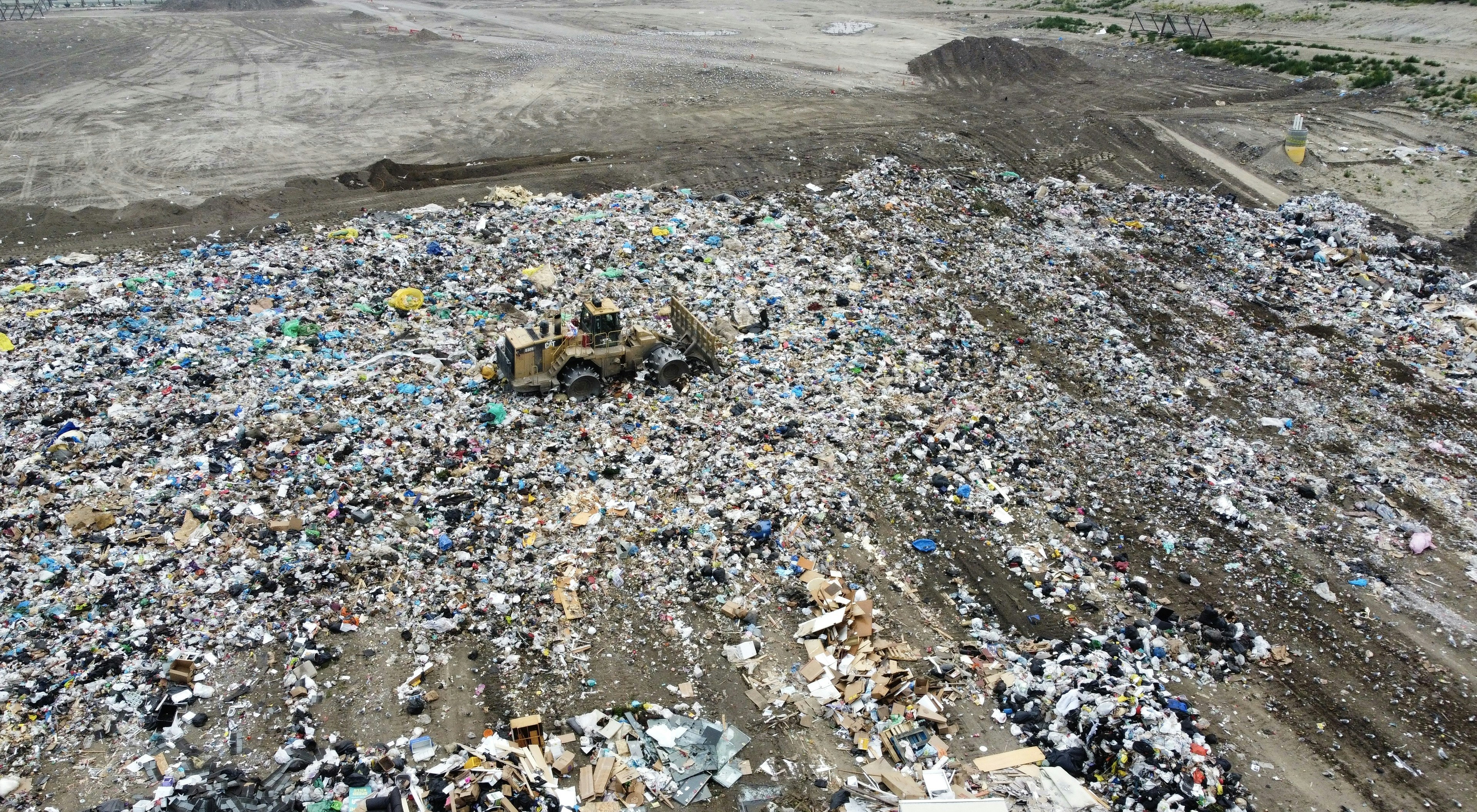 Bulldozer compacting trash at a large landfill site.