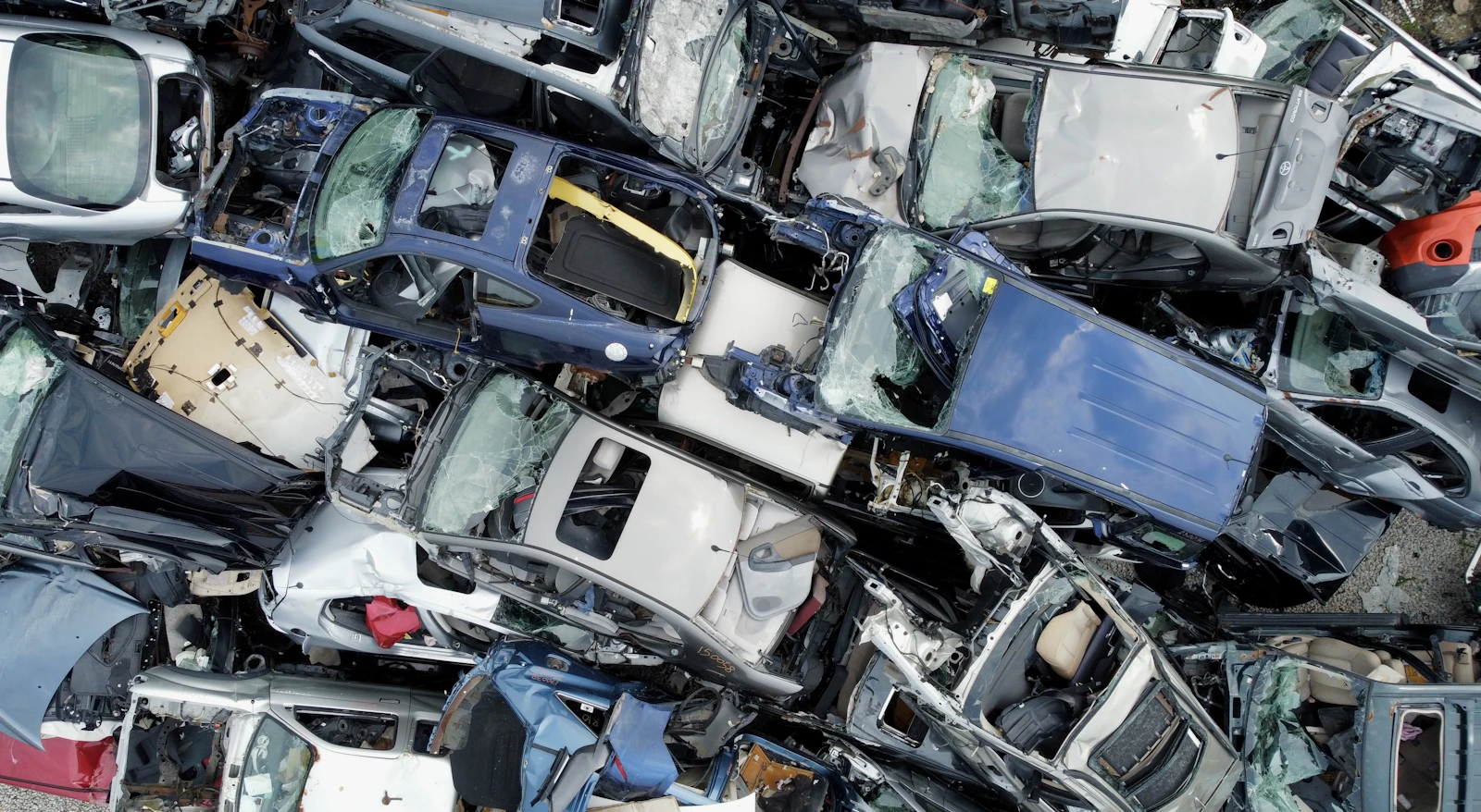 Aerial of crushed donor cars stacked in the salvage yard, steel and cream body panels