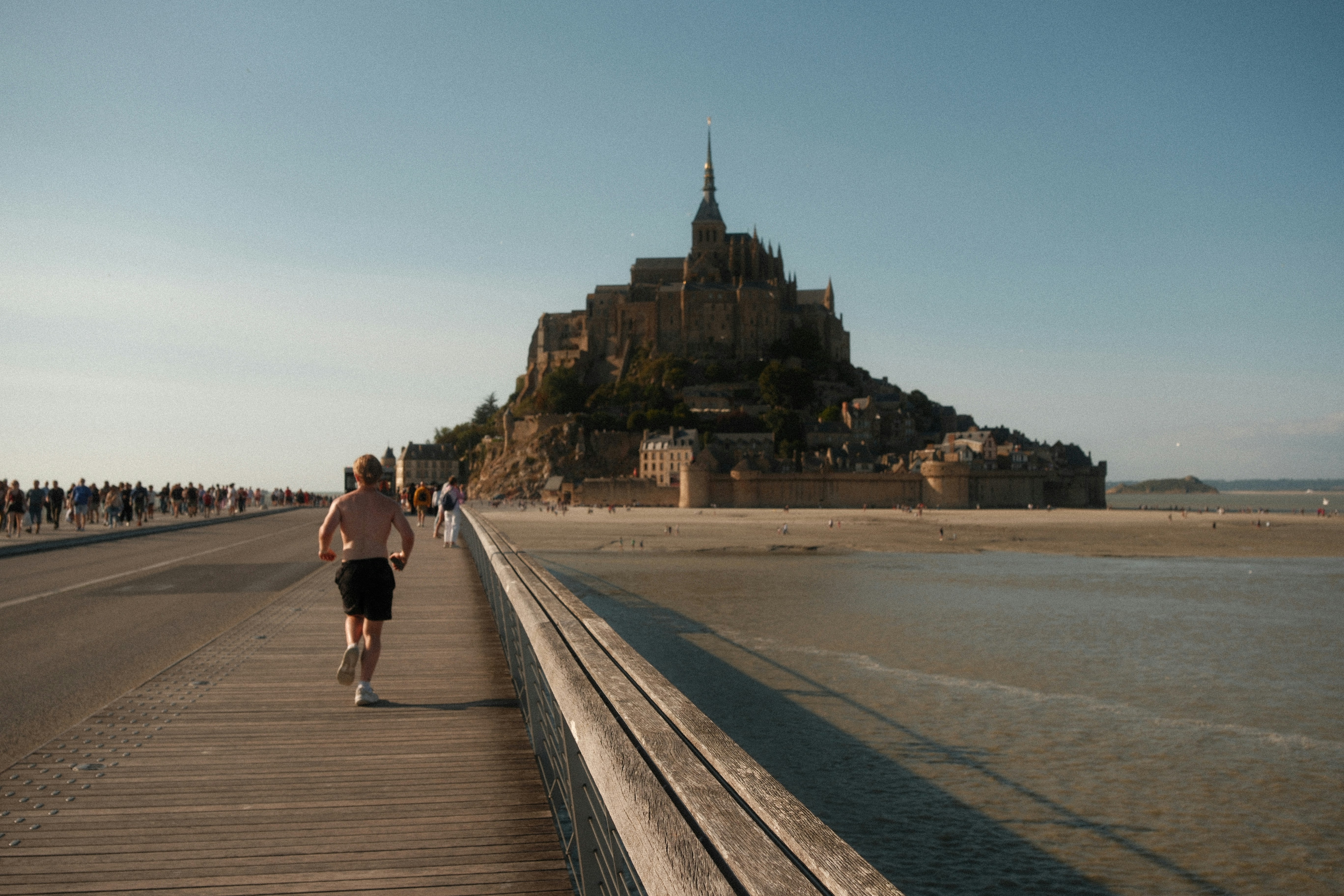 Homme courant vers le Mont Saint-Michel par une journée ensoleillée