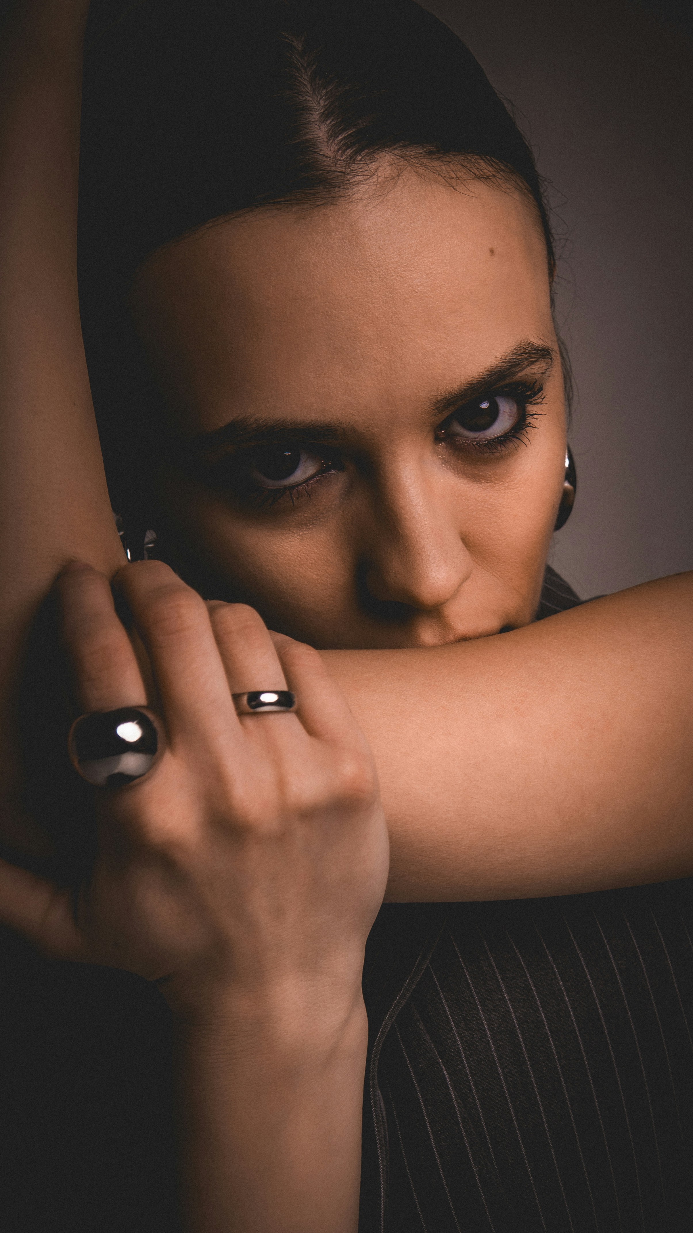 Woman with rings covering mouth with arm