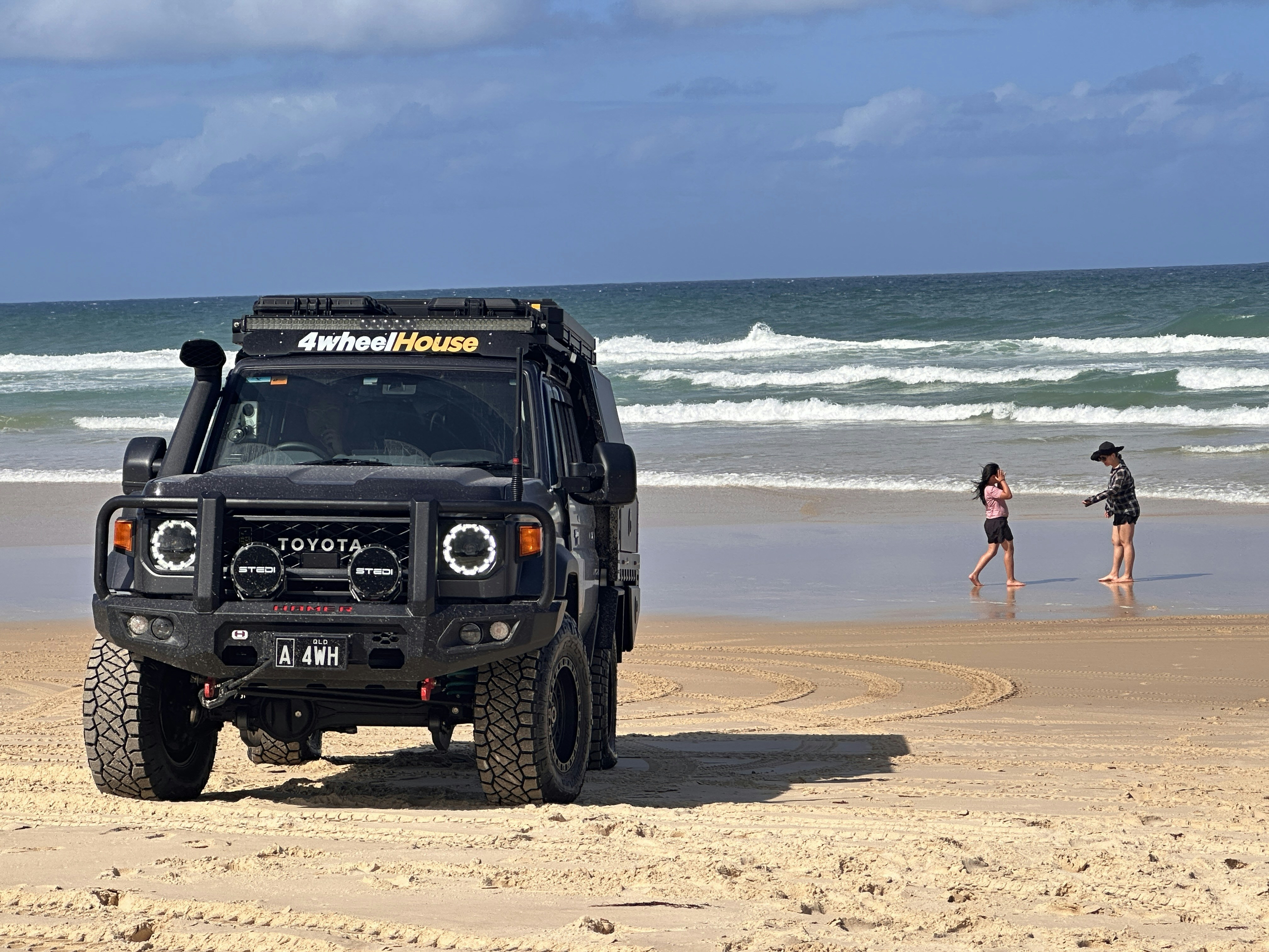 Off-road vehicle parked on a sandy beach near ocean.