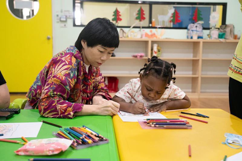 An adult and child draw together at a small wooden table
