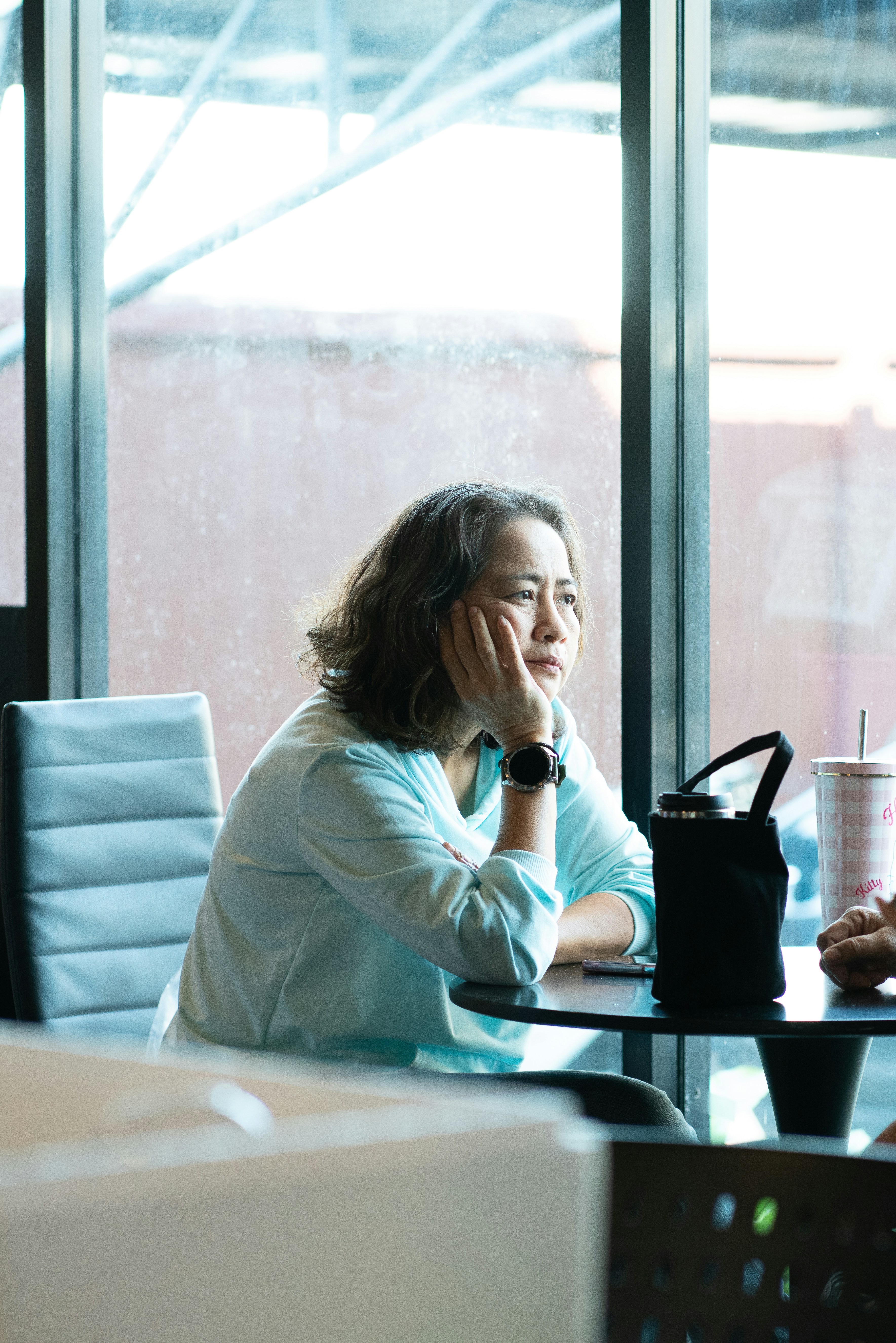 Frau sitzt an einem Tisch mit der Hand am Kinn
