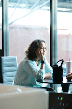 Woman sitting at a table with hand on chin
