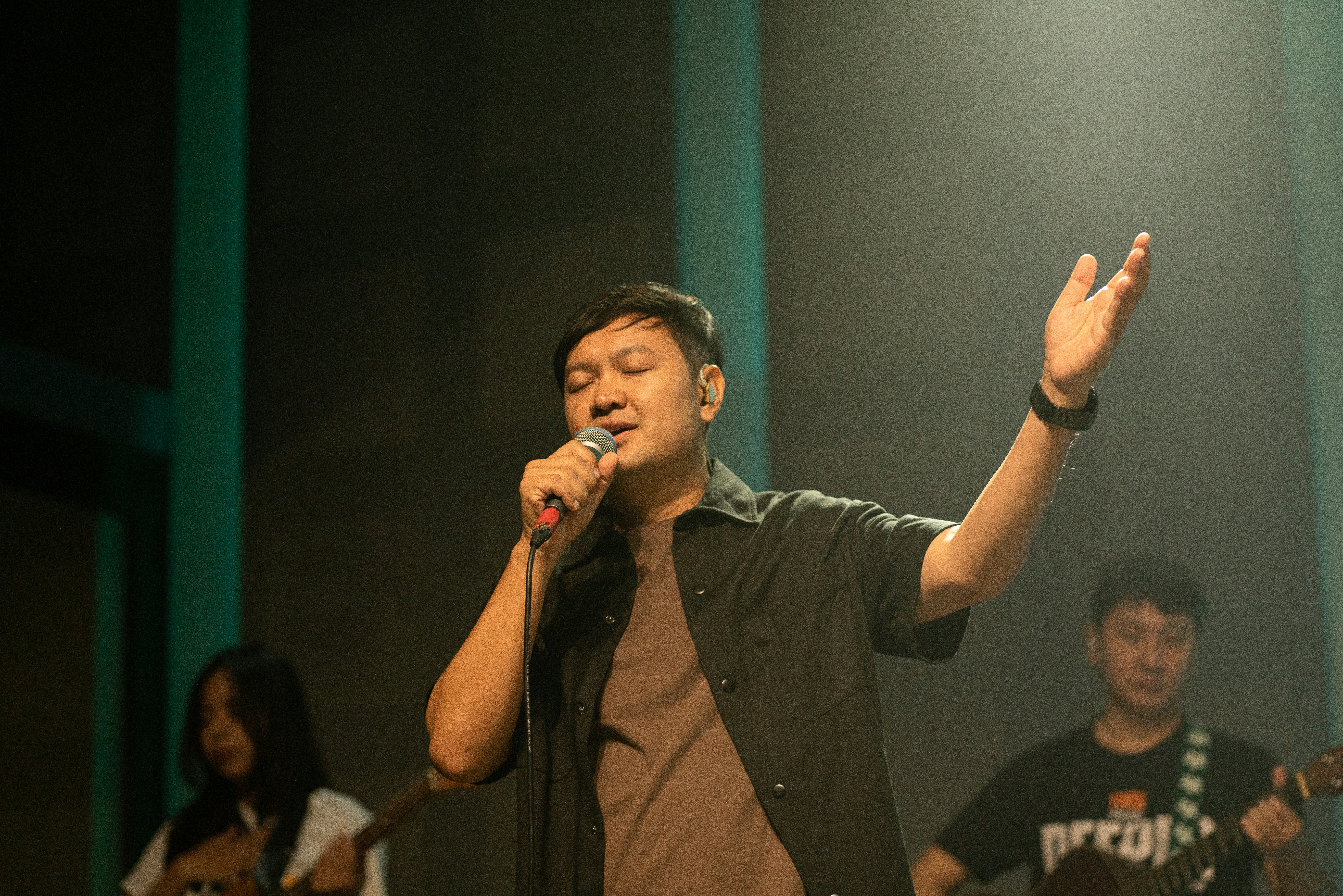 A man sings into a microphone on stage.