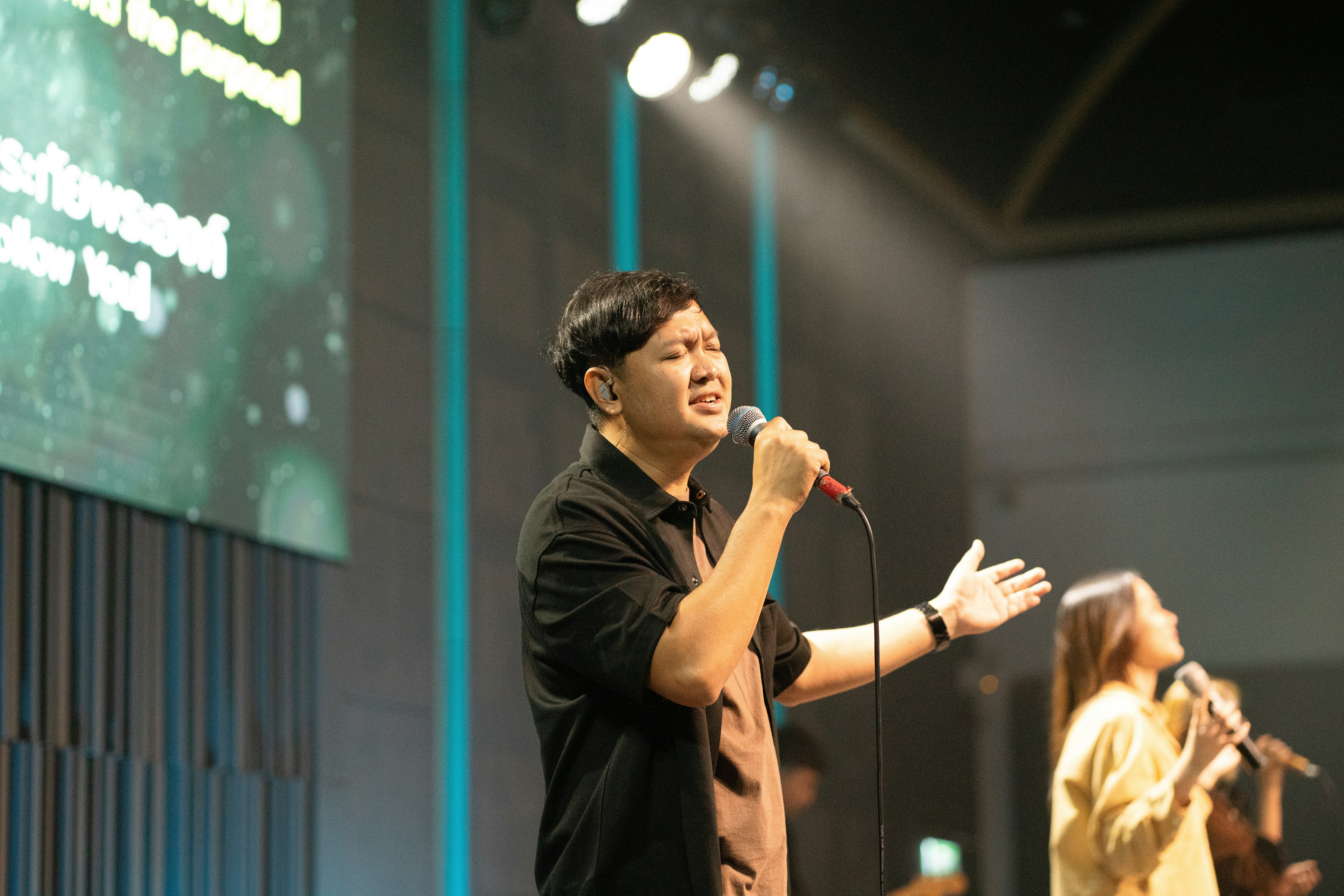 Man singing passionately into a microphone on stage.