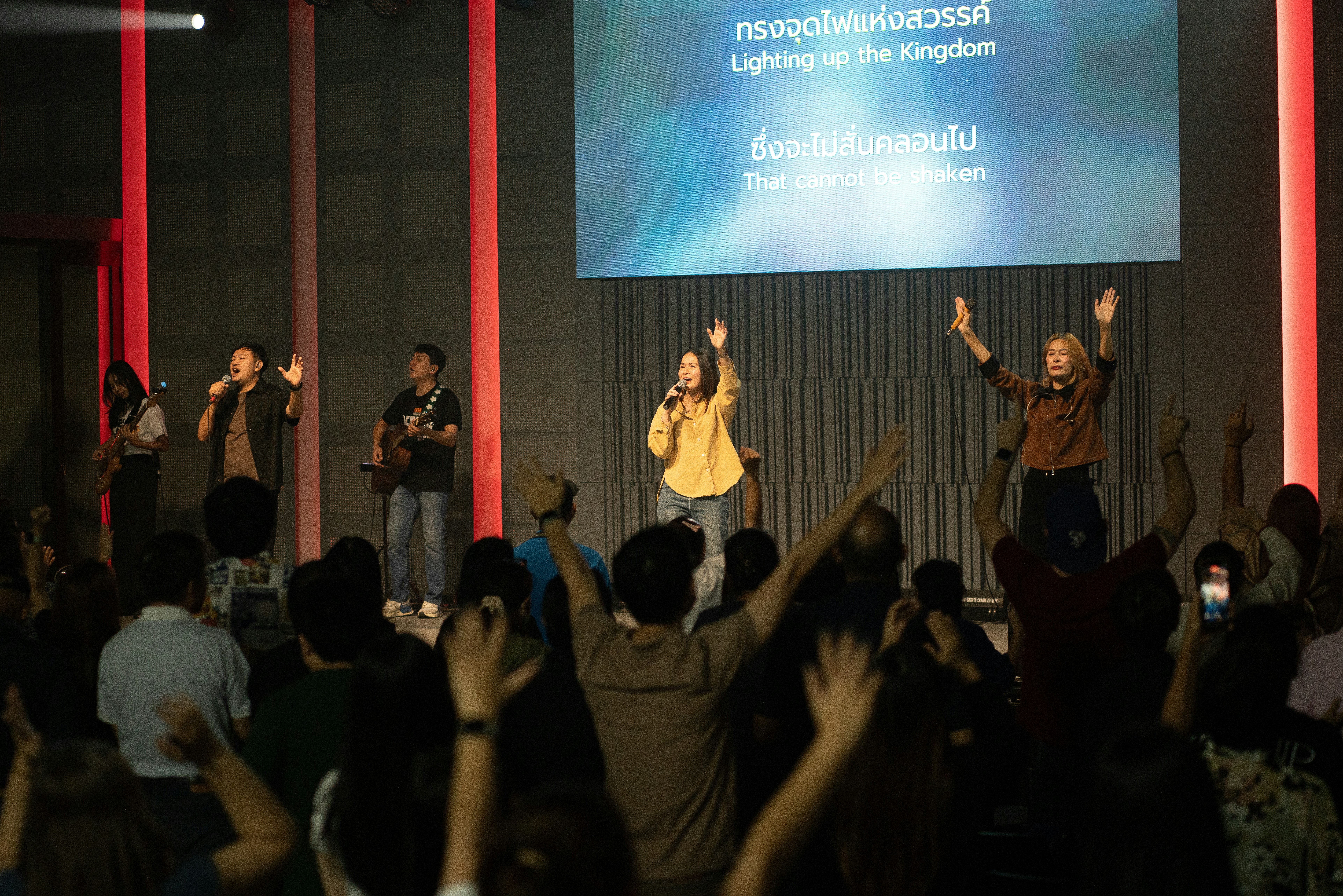 Worship band performing on stage with audience raising hands