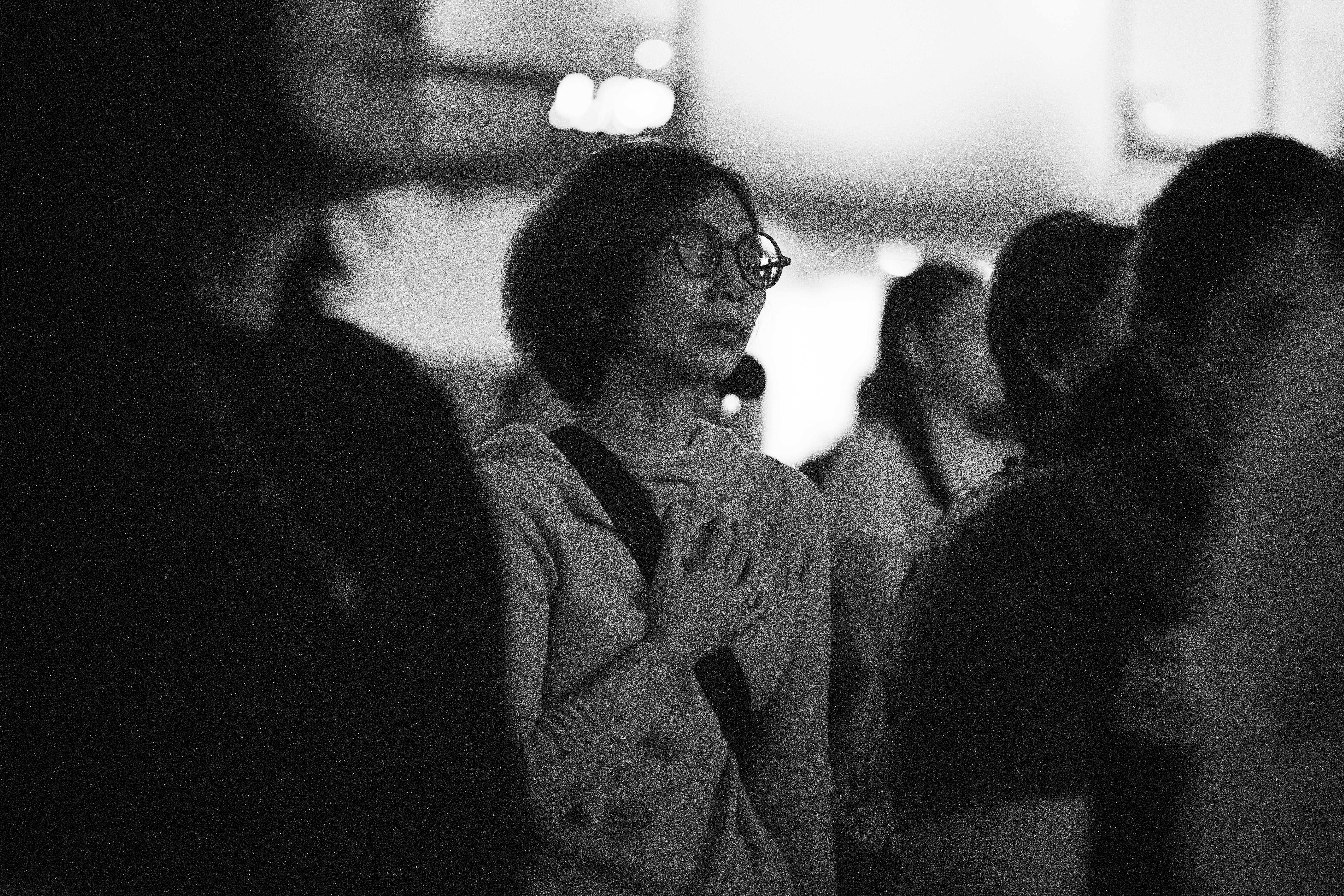 Woman in glasses with hand on chest looking away
