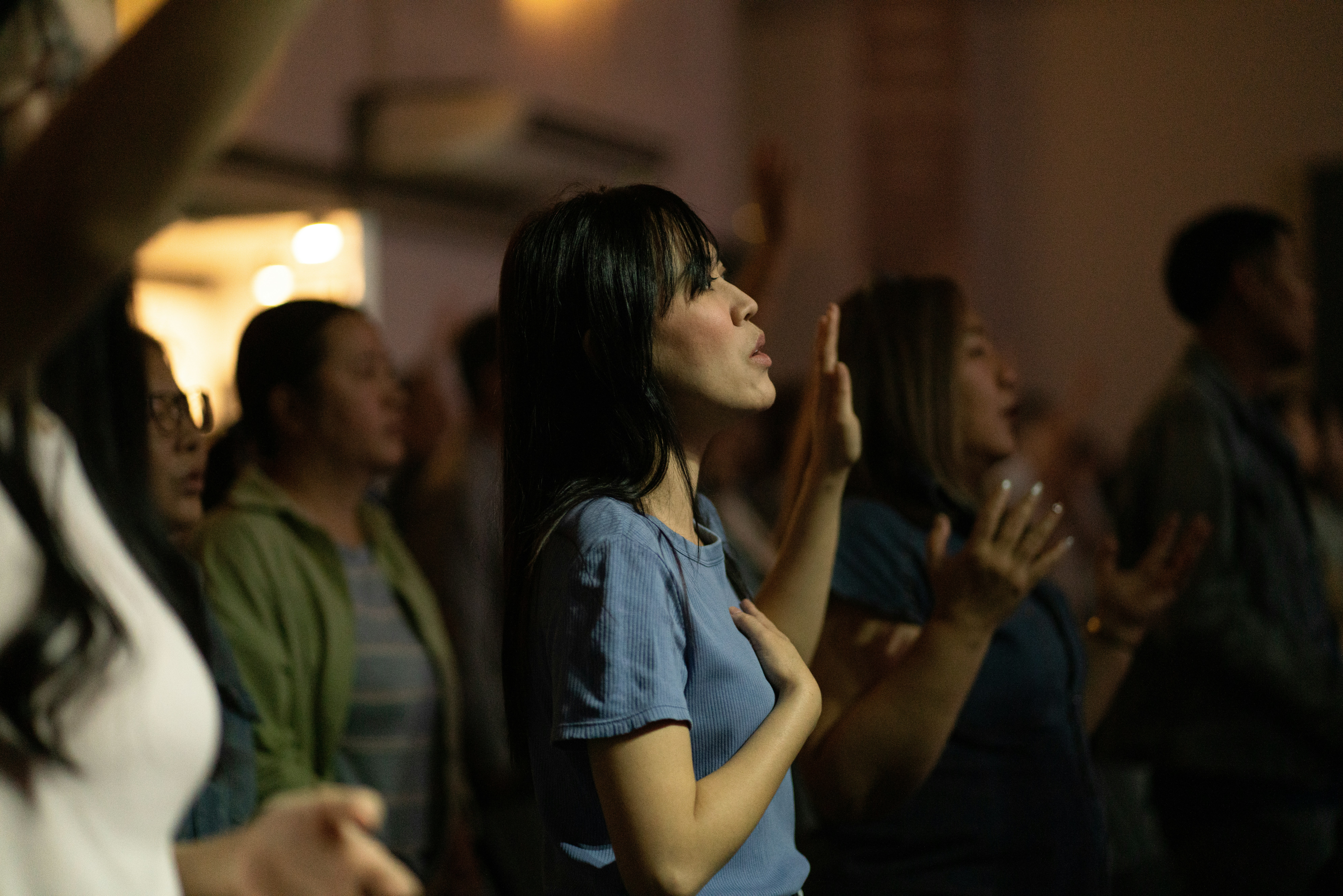 A woman with hands raised in worship during a service.