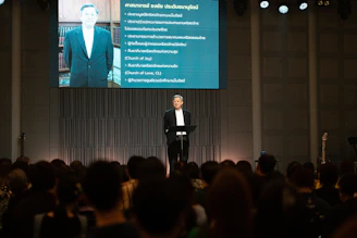 Man in suit speaks at podium in front of audience.