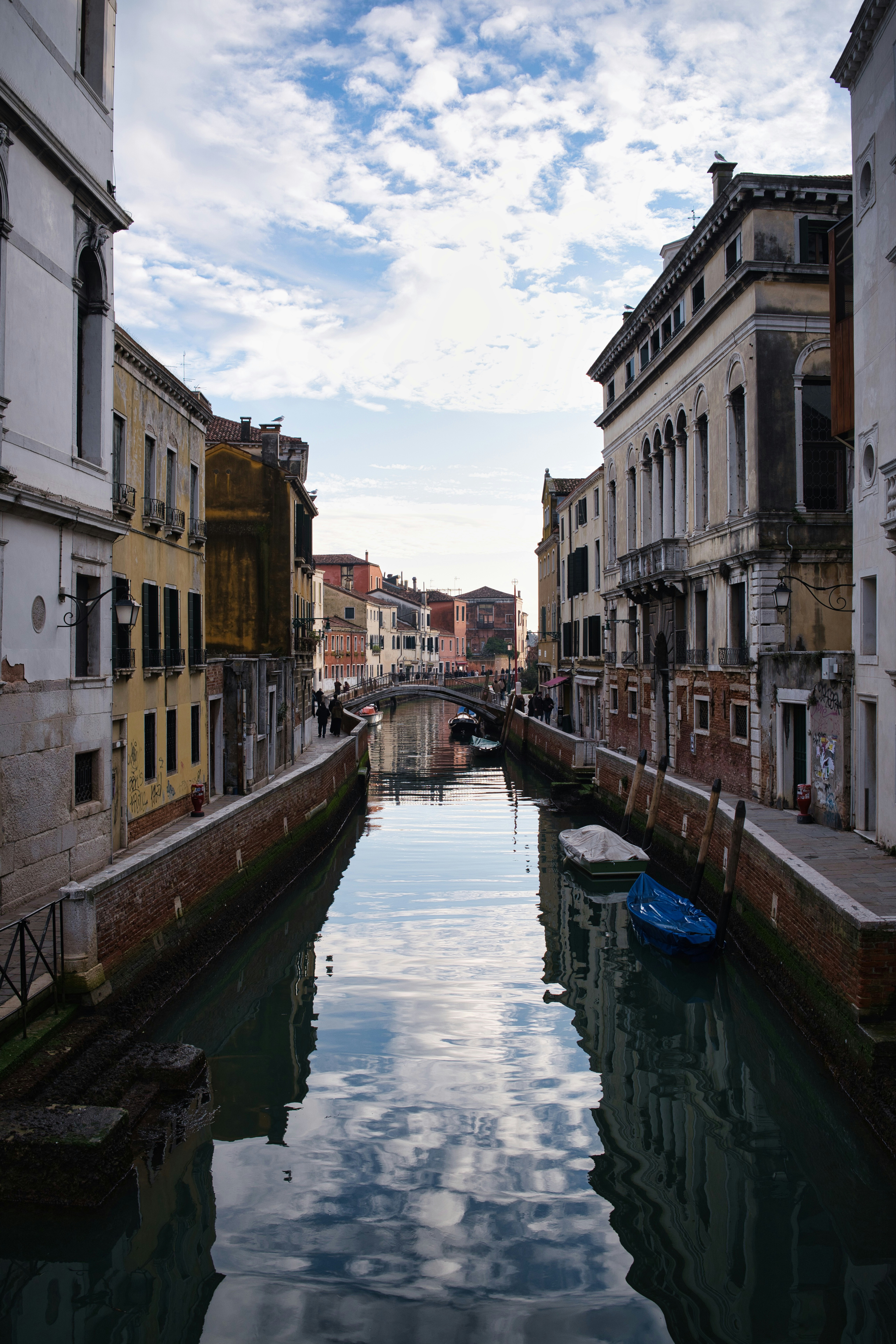 Canal lined with old buildings in venice under cloudy sky.